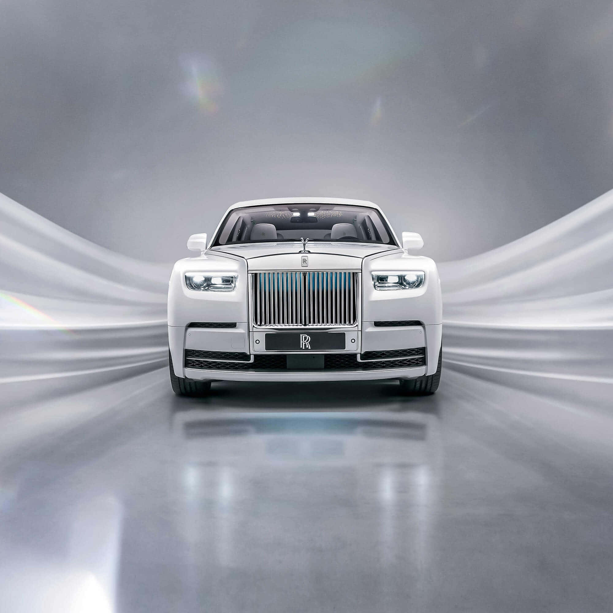 Rolls Royce 桌布 壁紙 — 一輛純白色的勞斯萊斯幻影正面朝前，車頭燈閃耀，背景是動態的銀色動態模糊效果。