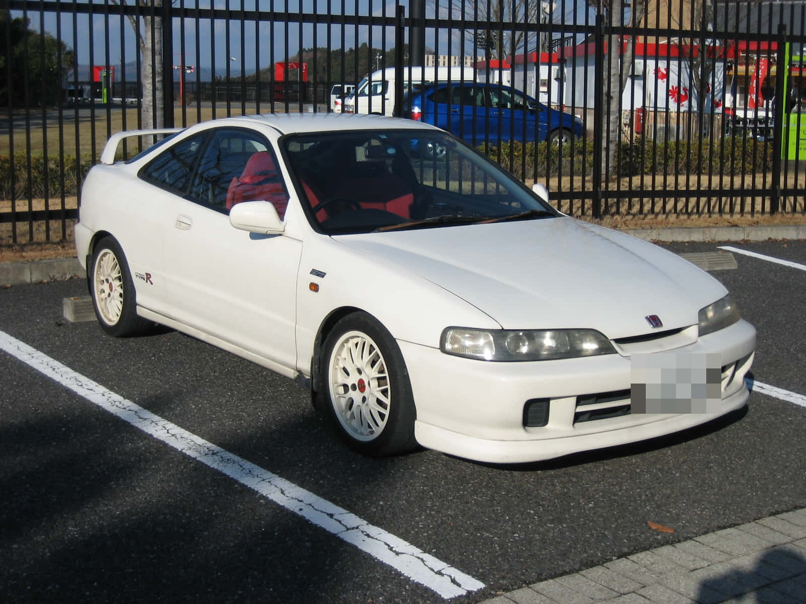 Honda Integra 桌布 壁紙 — 一輛純白色的本田 Integra Type R 雙門跑車停放在陽光明媚的瀝青停車場，紅色內飾透過車窗可見。