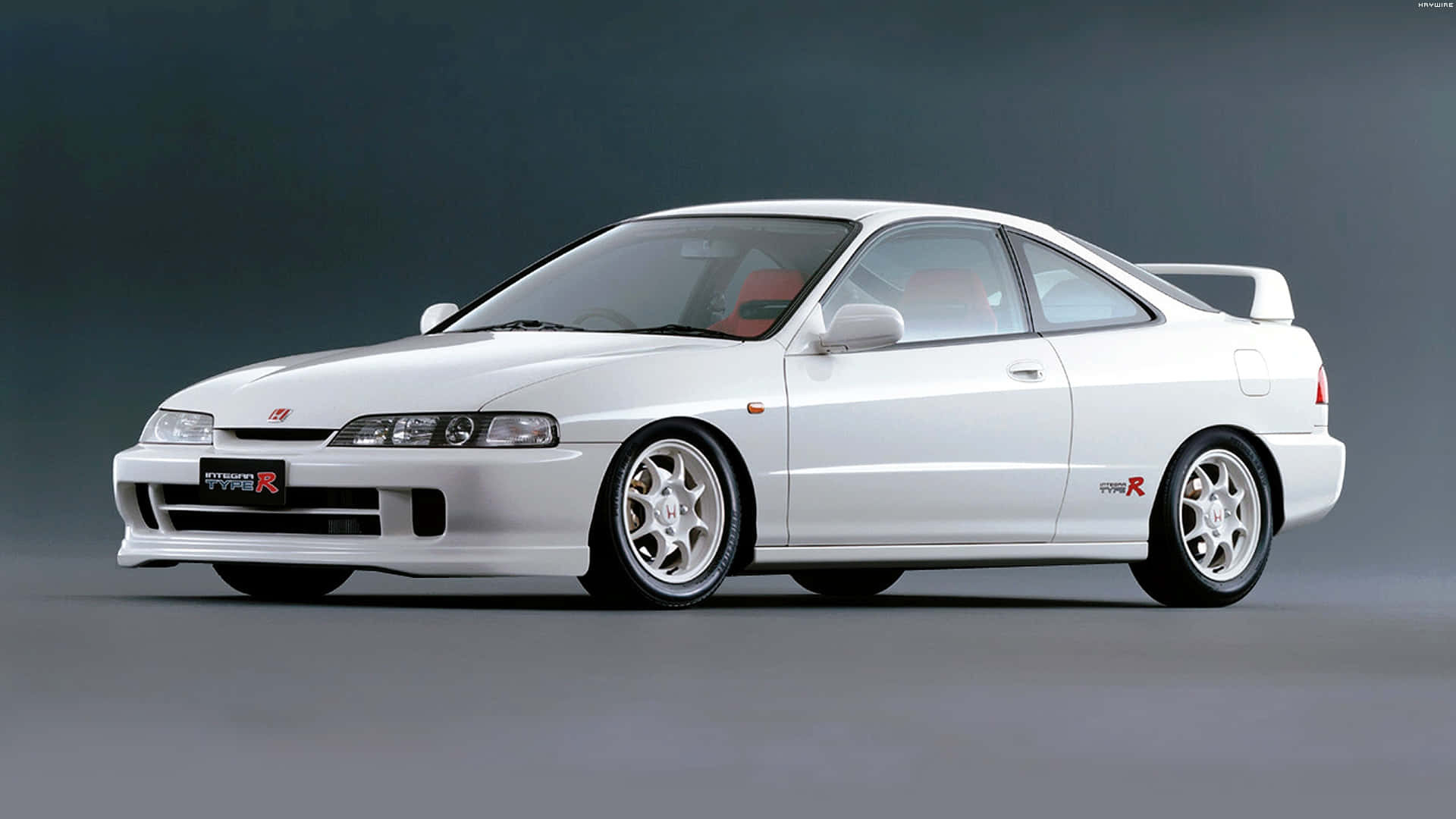Honda Integra 桌布 壁紙 — 一輛純白色的本田Integra Type R運動轎跑車，配備紅色內飾和改裝輪圈，在深灰色工作室背景前展示。
