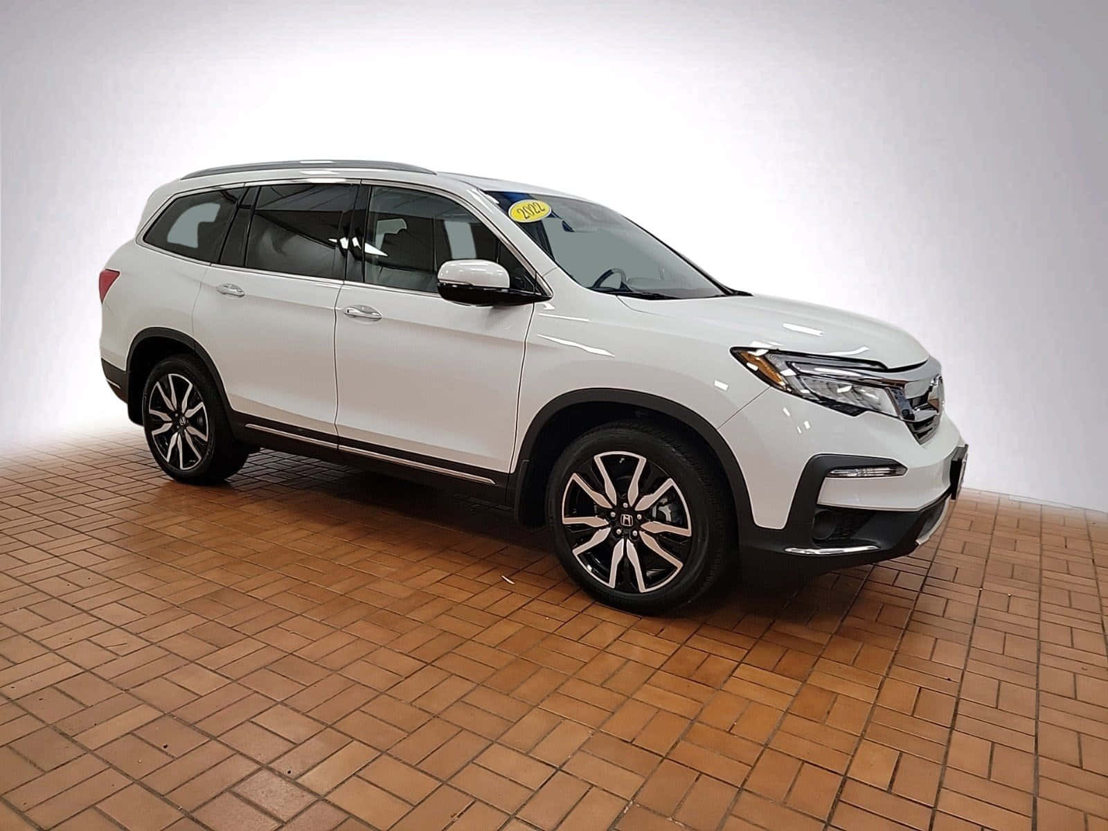 Honda Pilot 桌布 壁紙 — 一輛純白色的本田Pilot SUV在赤陶磚地板上展示，背景為簡約的工作室背景。