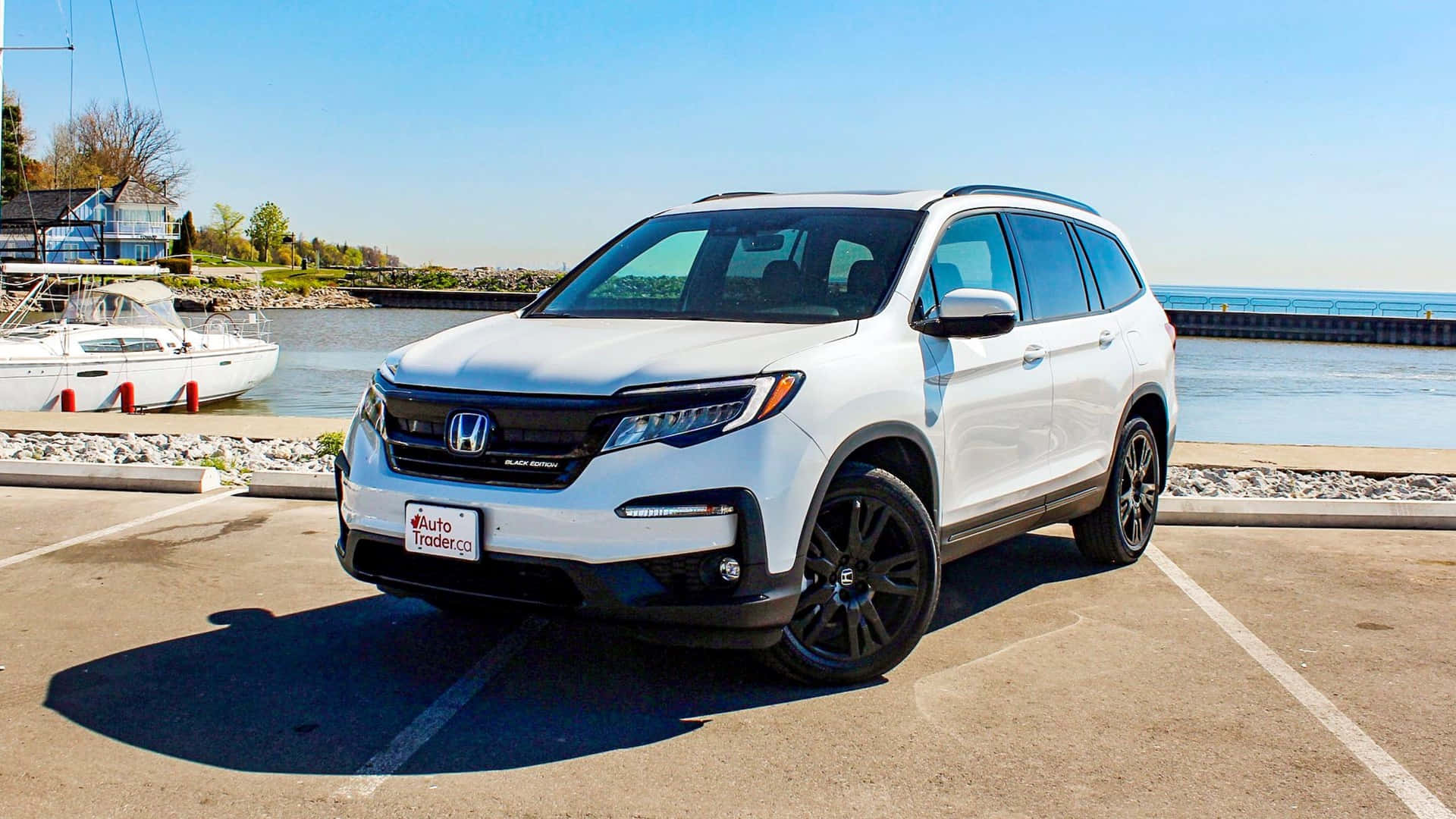 Honda Pilot 桌布 壁紙 — 一輛純白色的本田Pilot SUV停泊在陽光明媚的海濱地段，旁邊停靠著一艘帆船。