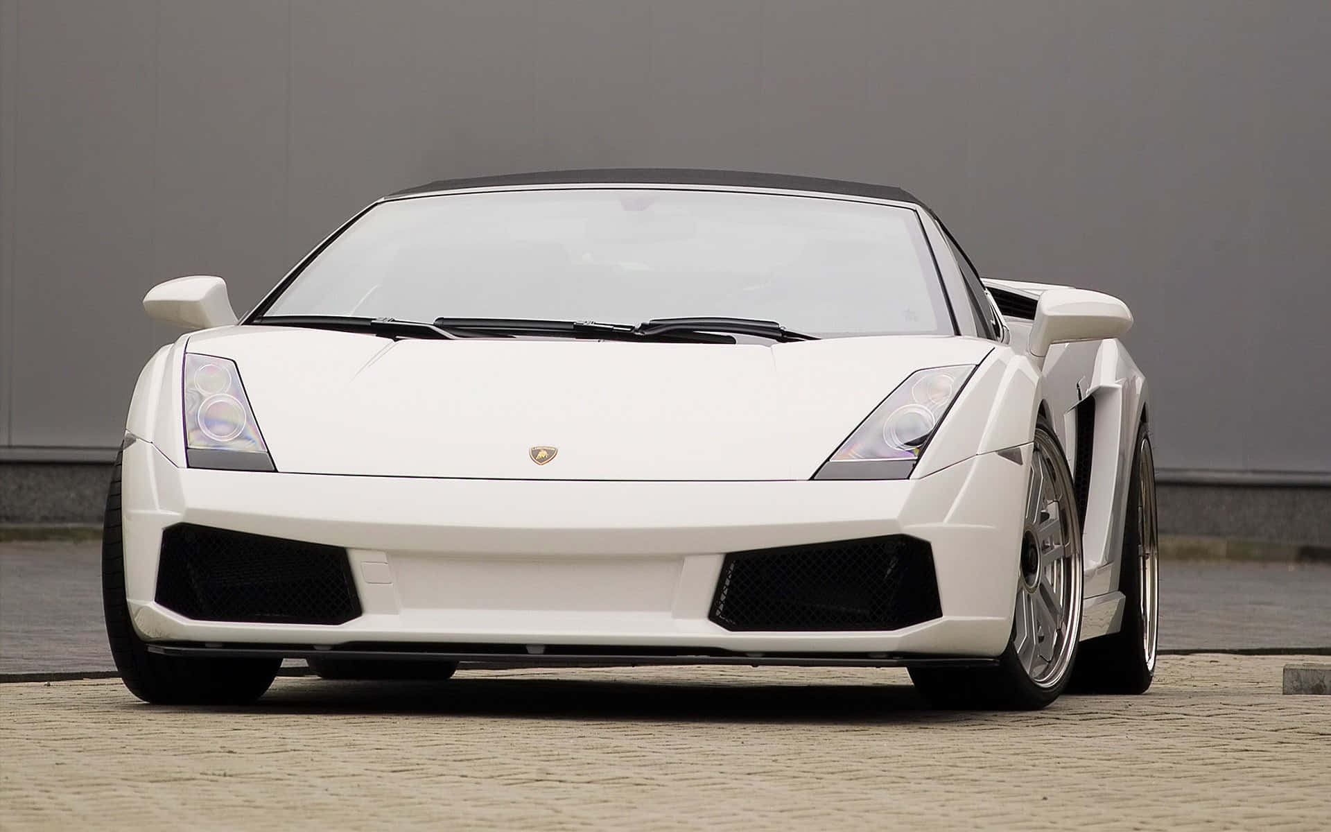 Lamborghini Gallardo 桌布 壁紙 — 一輛純白色的林寶堅尼 Gallardo Spyder 停泊在鵝卵石地面上，背景是簡約的灰色牆壁。