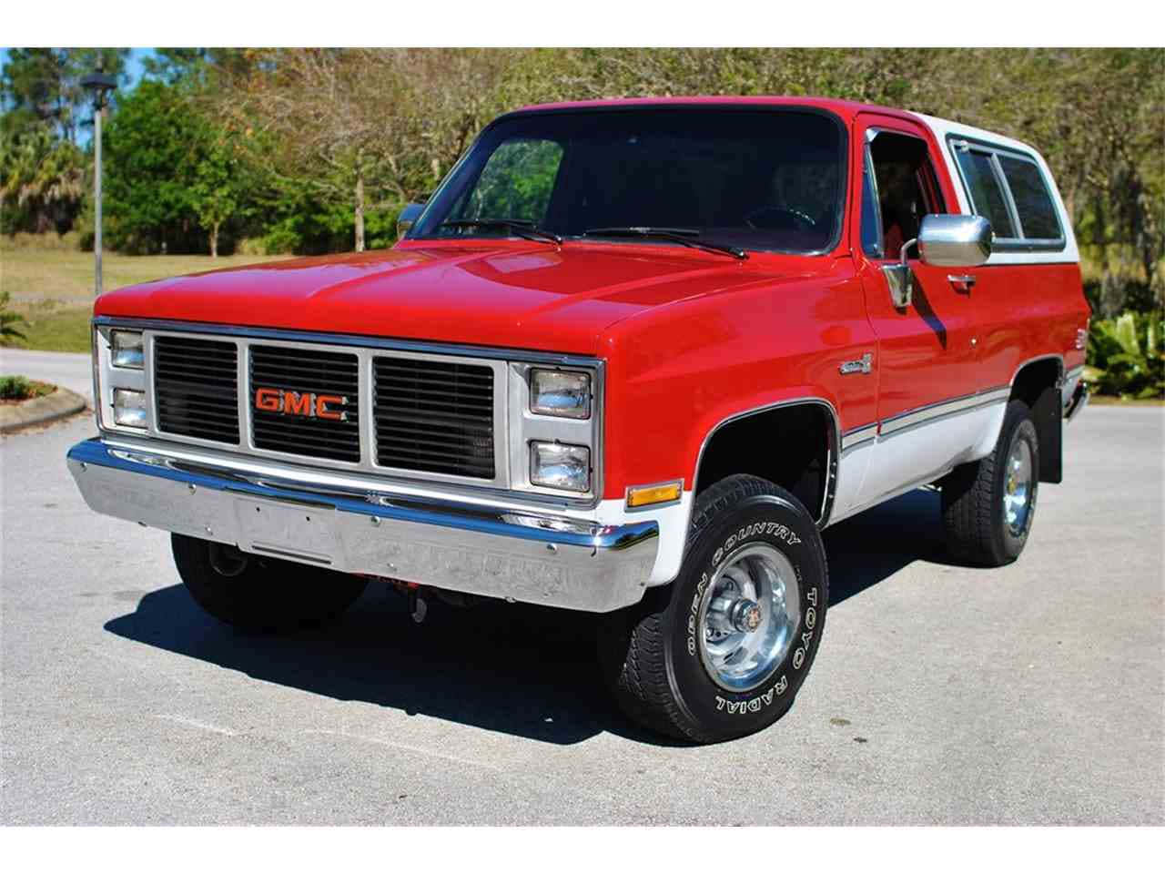Gmc Jimmy 桌布 壁紙 — 一輛經典紅白相間的GMC皮卡車停在瀝青路面上，背景有樹木，在明亮的陽光下。