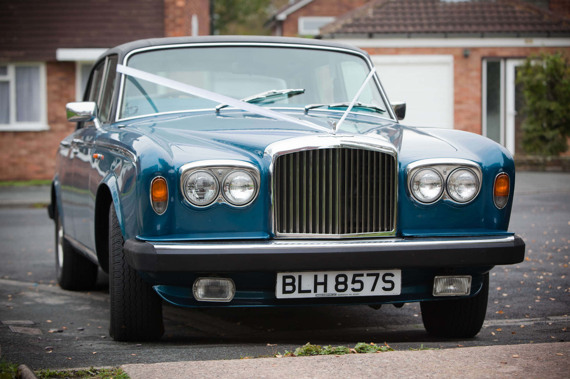Bentley T2 桌布 壁紙 — 一輛經典藍色賓利婚車，帶有白色絲帶，停放在住宅街道上。