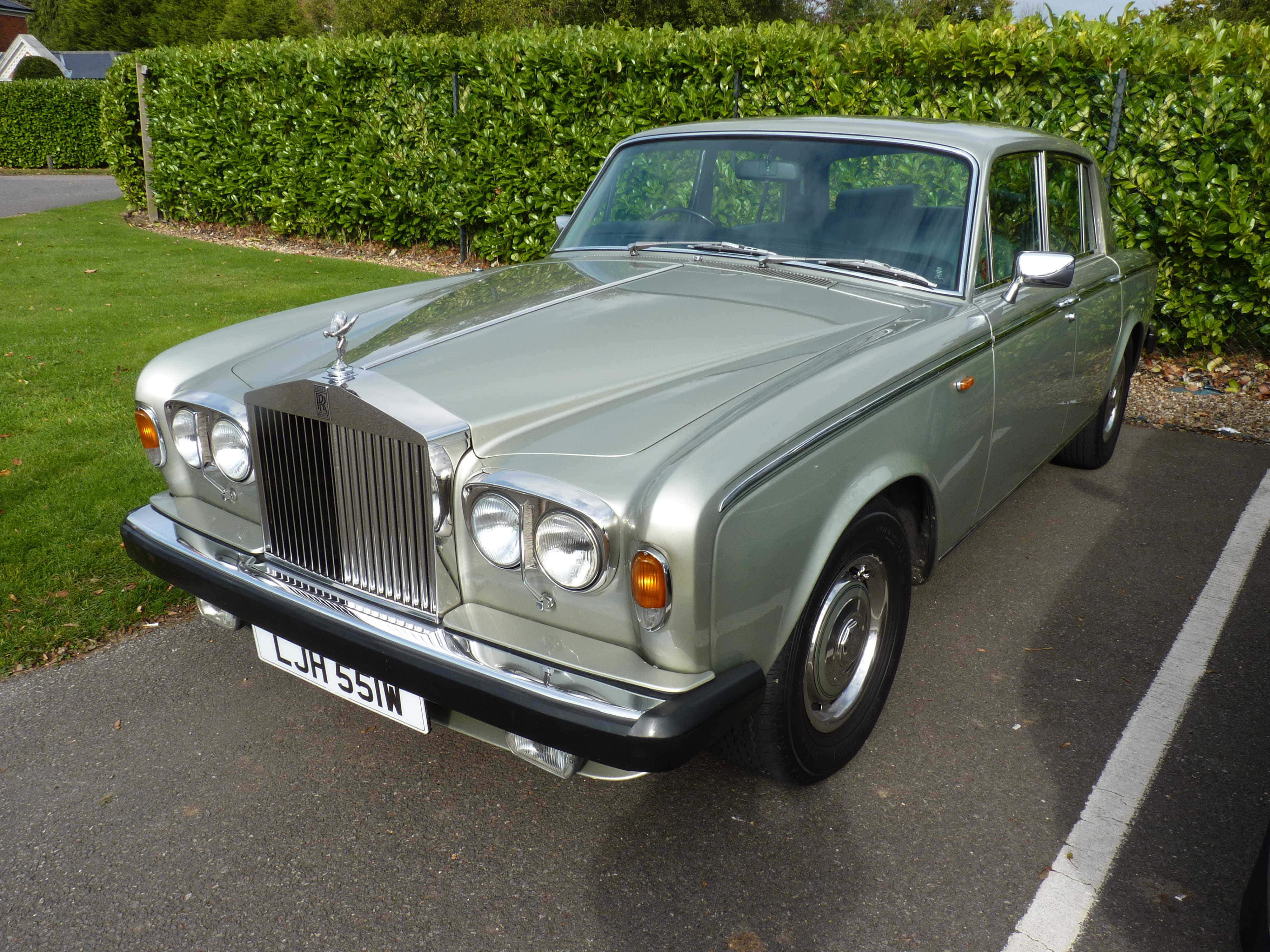 Bentley T2 桌布 壁紙 — 一輛經典銀色勞斯萊斯停泊在鋪砌的車道上，旁邊是茂密的綠色樹籬和草坪。