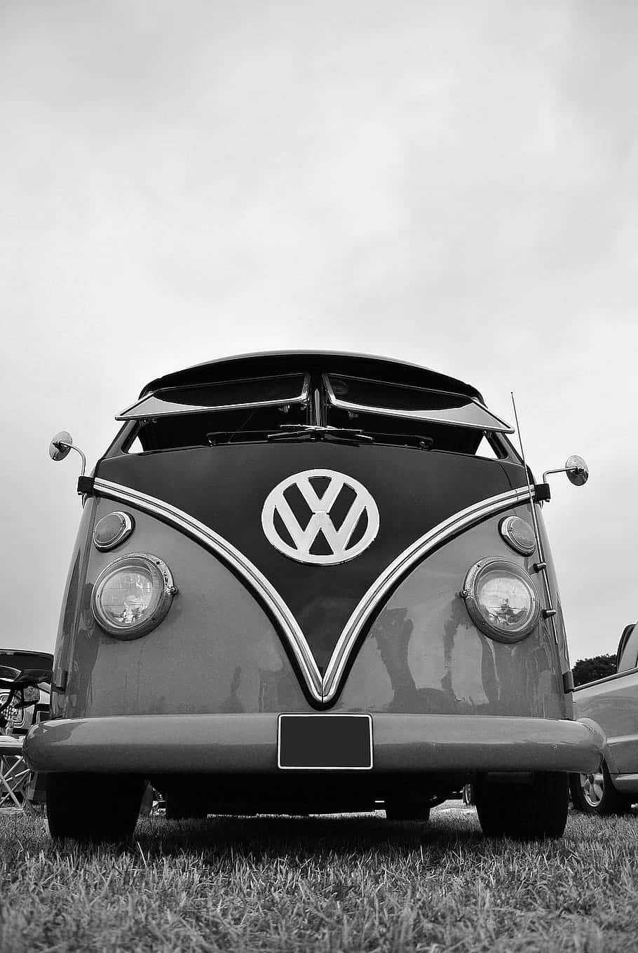 Black And White Vintage Car 桌布 壁紙 — 一輛經典黑白配色的福士偉根巴士，帶有鍍鉻裝飾，在陰天下的草地上顯眼地停放。