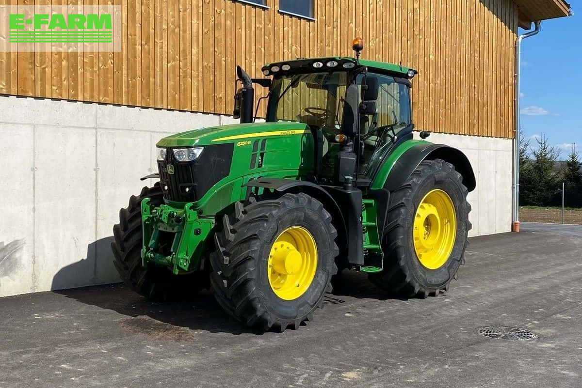 John Deere 桌布 壁紙 — 一輛綠色和黃色的約翰迪爾拖拉機停放在木製穀倉前，天空湛藍。