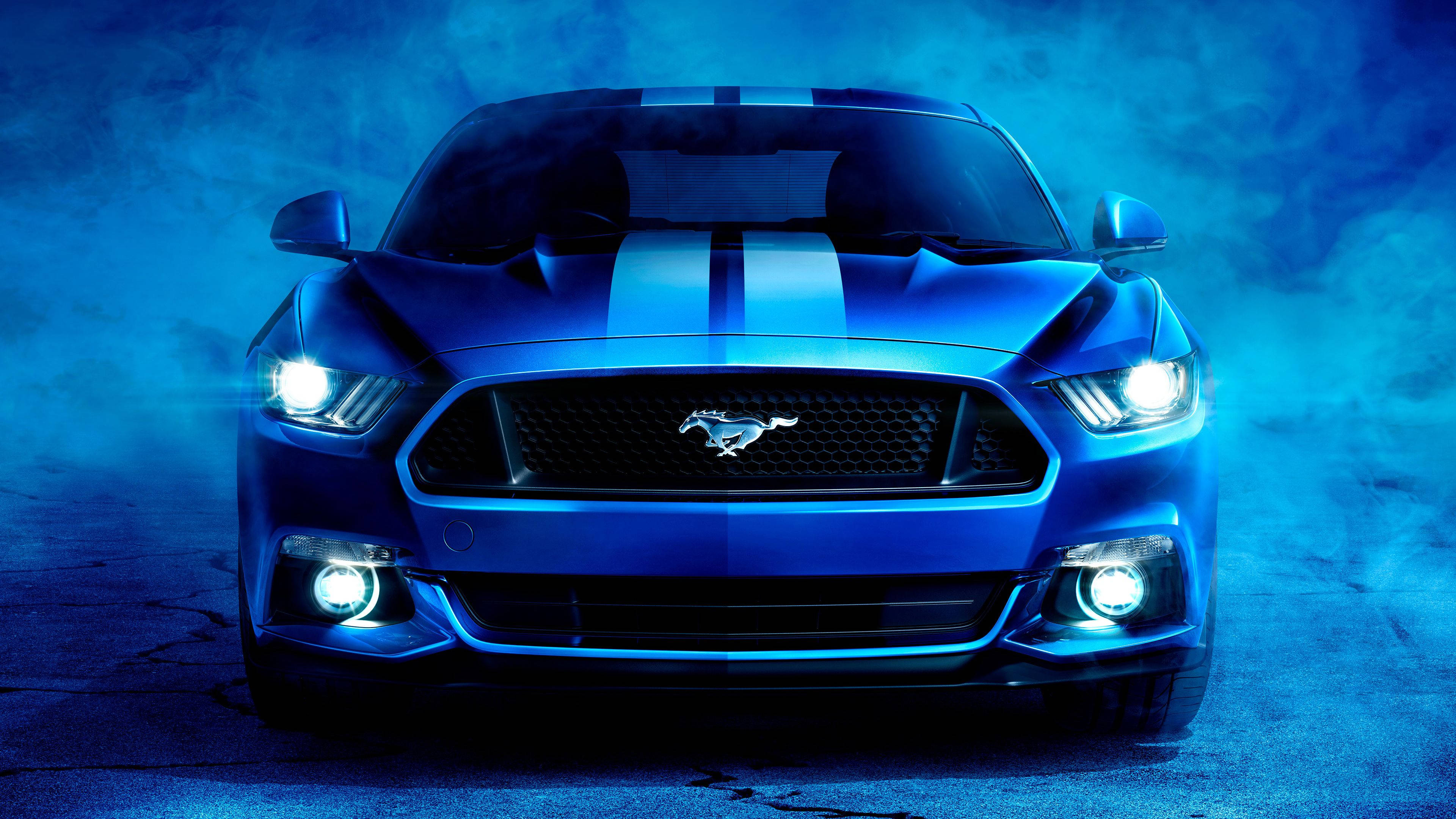 mustang HD 桌布 壁紙 — 一輛藍色福特野馬帶有賽車條紋，在戲劇性的藍色燈光下於旋轉煙霧中發光。