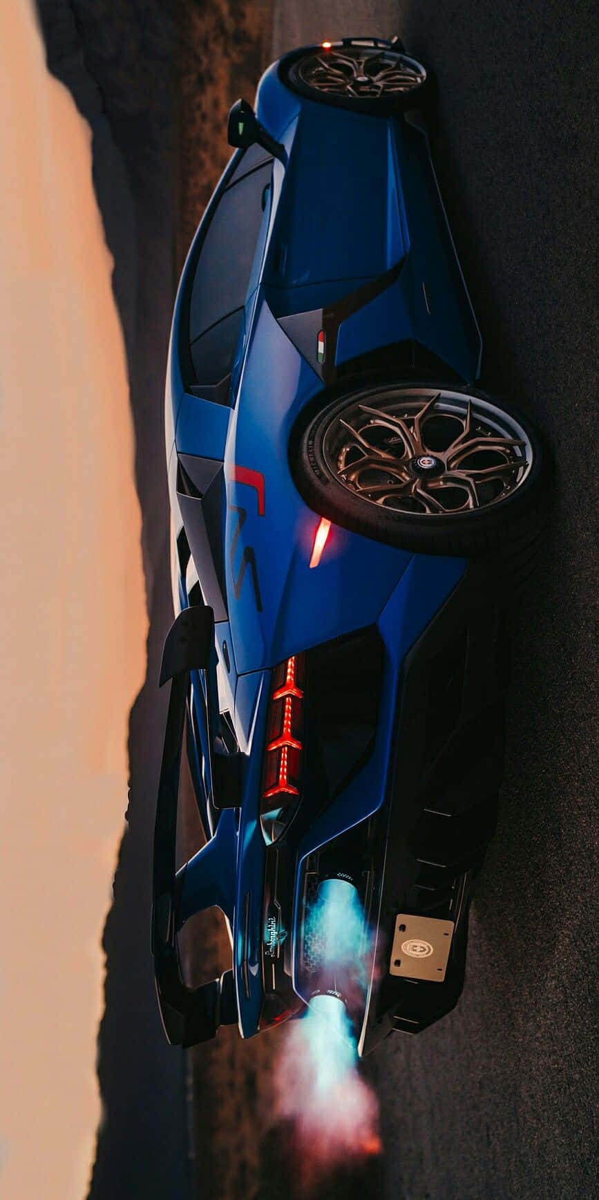 Minimalist Car 桌布 壁紙 — 一輛藍色跑車在日落時分沿沙漠公路奔馳，排氣管噴出熾熱火焰。