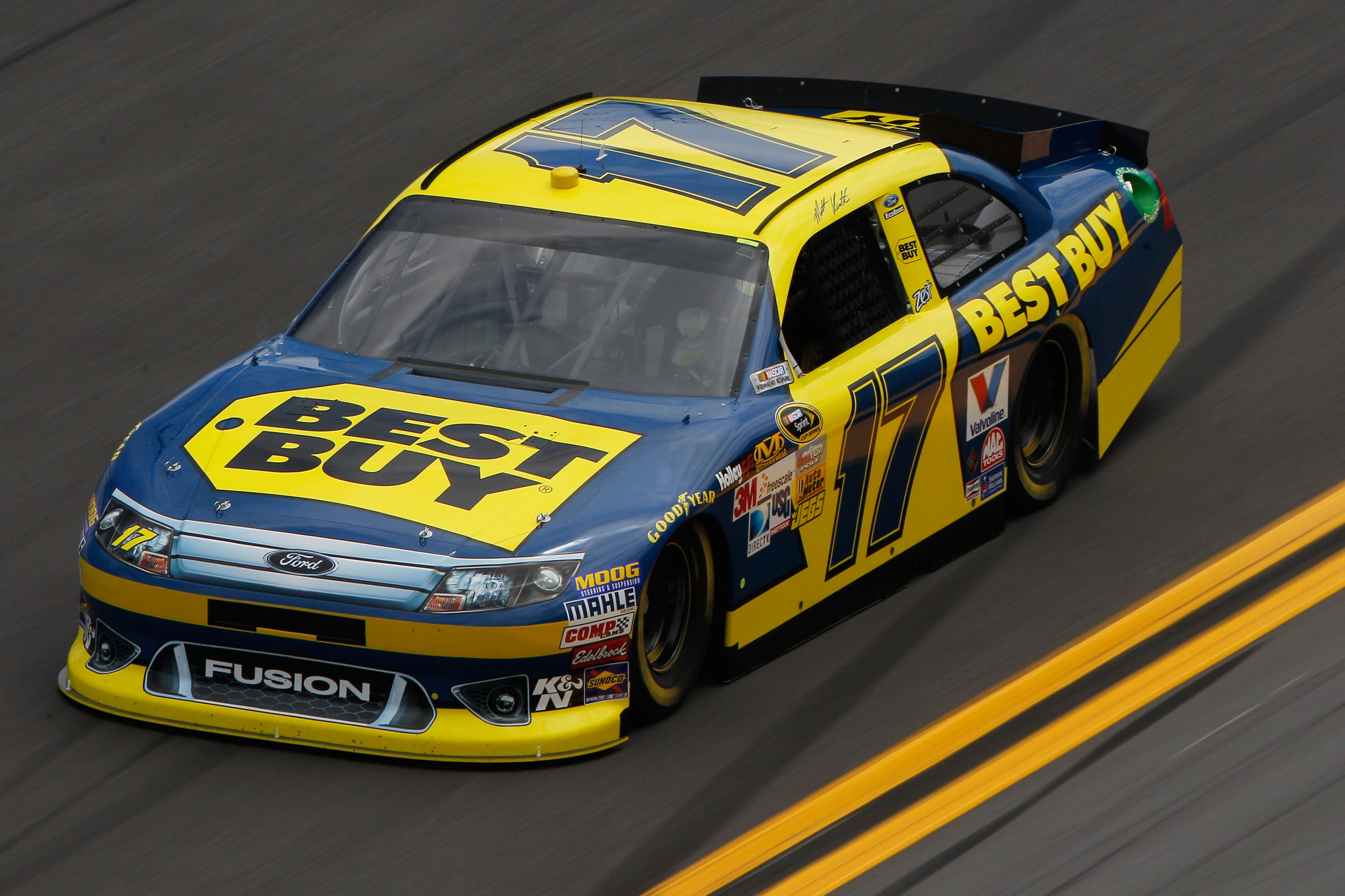 NASCAR Best Buy 壁紙 — 一輛藍黃配色、由Best Buy贊助的NASCAR Fusion賽車在賽道上疾馳，帶有動態模糊效果。