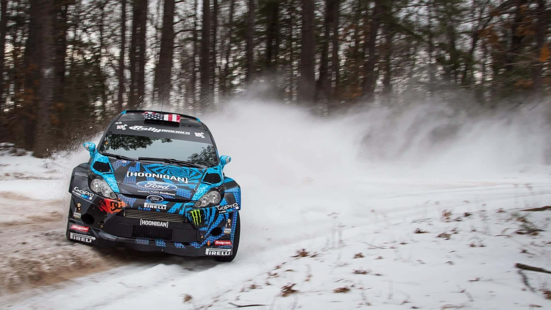 Ice Racing 桌布 壁紙 — 一輛藍黑相間的拉力賽車在白雪覆蓋的森林小徑上飛馳，激起大量雪和泥漿。