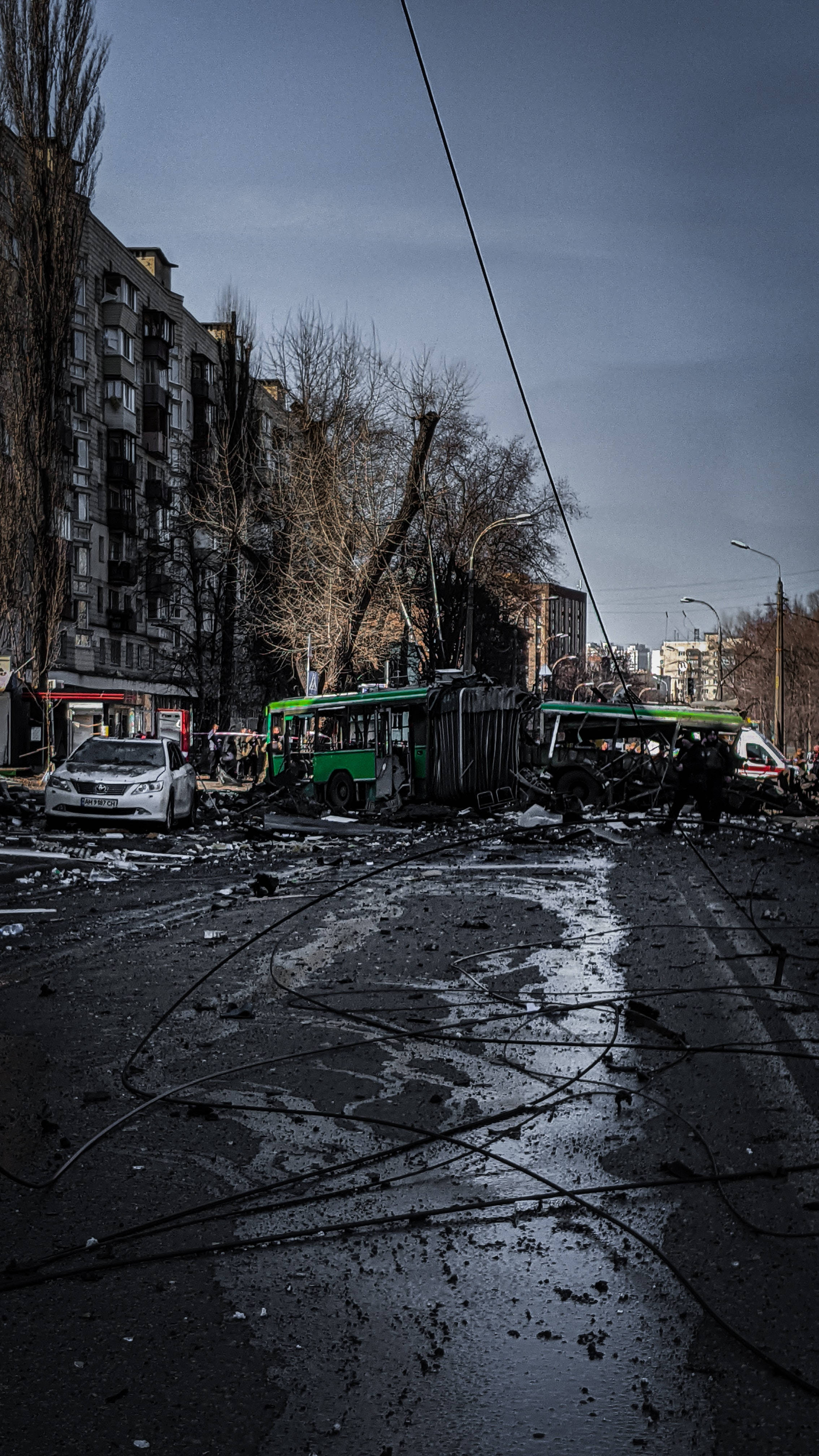Car Accident 桌布 壁紙 — 一輛被毀的綠色電車翻倒在廢墟般的城市街道上，碎片散落在灰色的天空下。