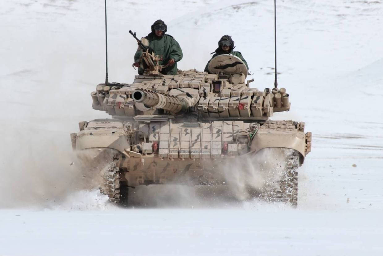 Indian Army 桌布 壁紙 — 一輛軍用坦克載著兩名士兵在雪地上高速行駛，濺起雪花。