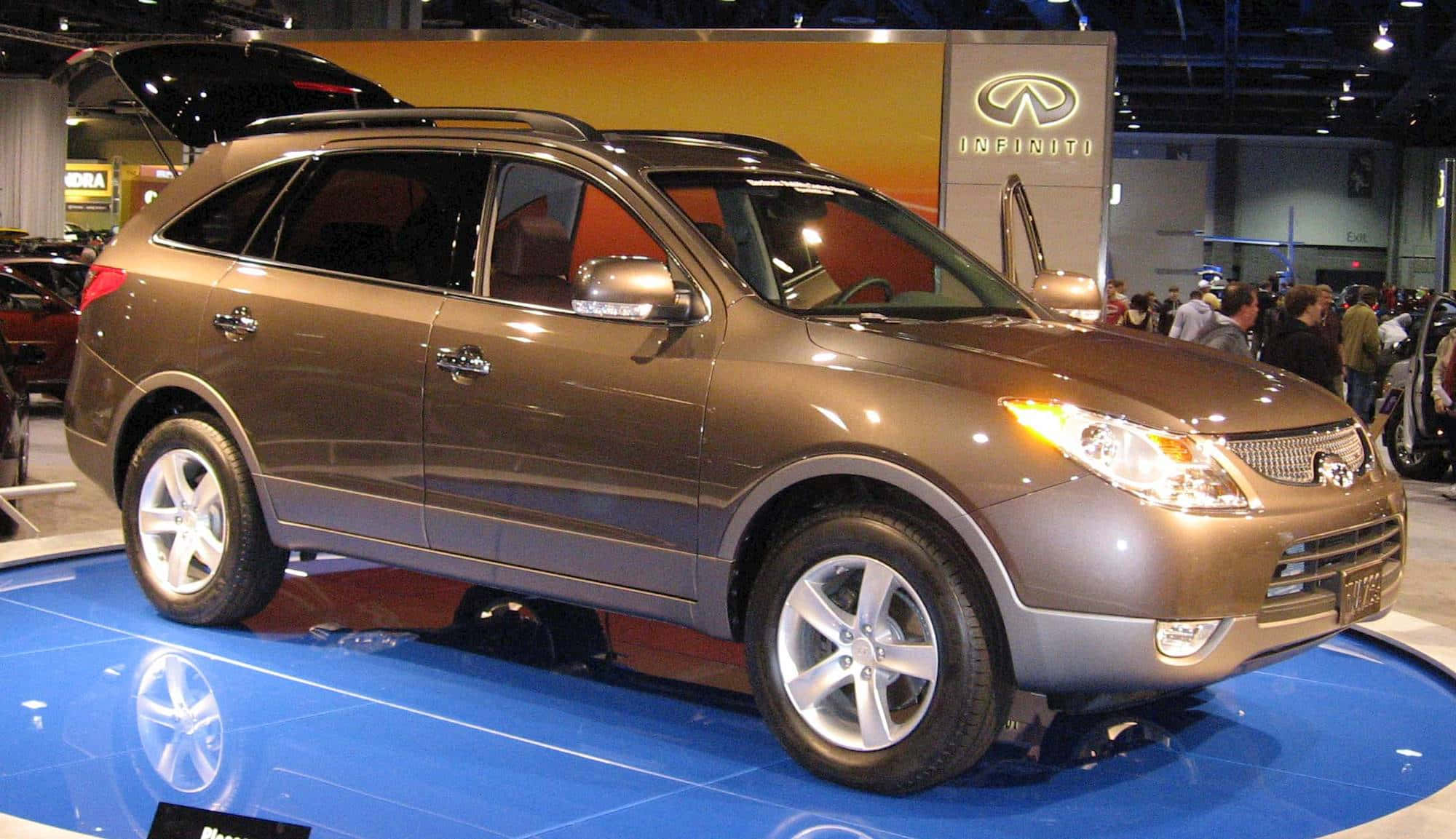 Hyundai Veracruz 桌布 壁紙 — 一輛金屬青銅色的Infiniti FX SUV在車展的藍色反光平台上，在明亮燈光下閃閃發光。