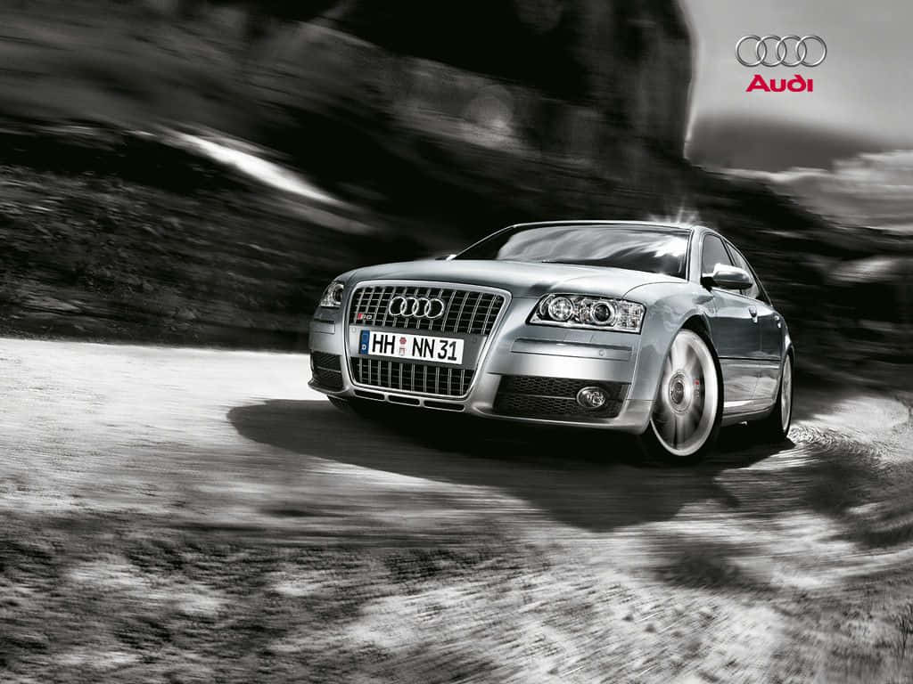 Audi S8 桌布 壁紙 — 一輛銀色 Audi 房車沿著蜿蜒的山路疾馳，動態模糊效果強調其動感。