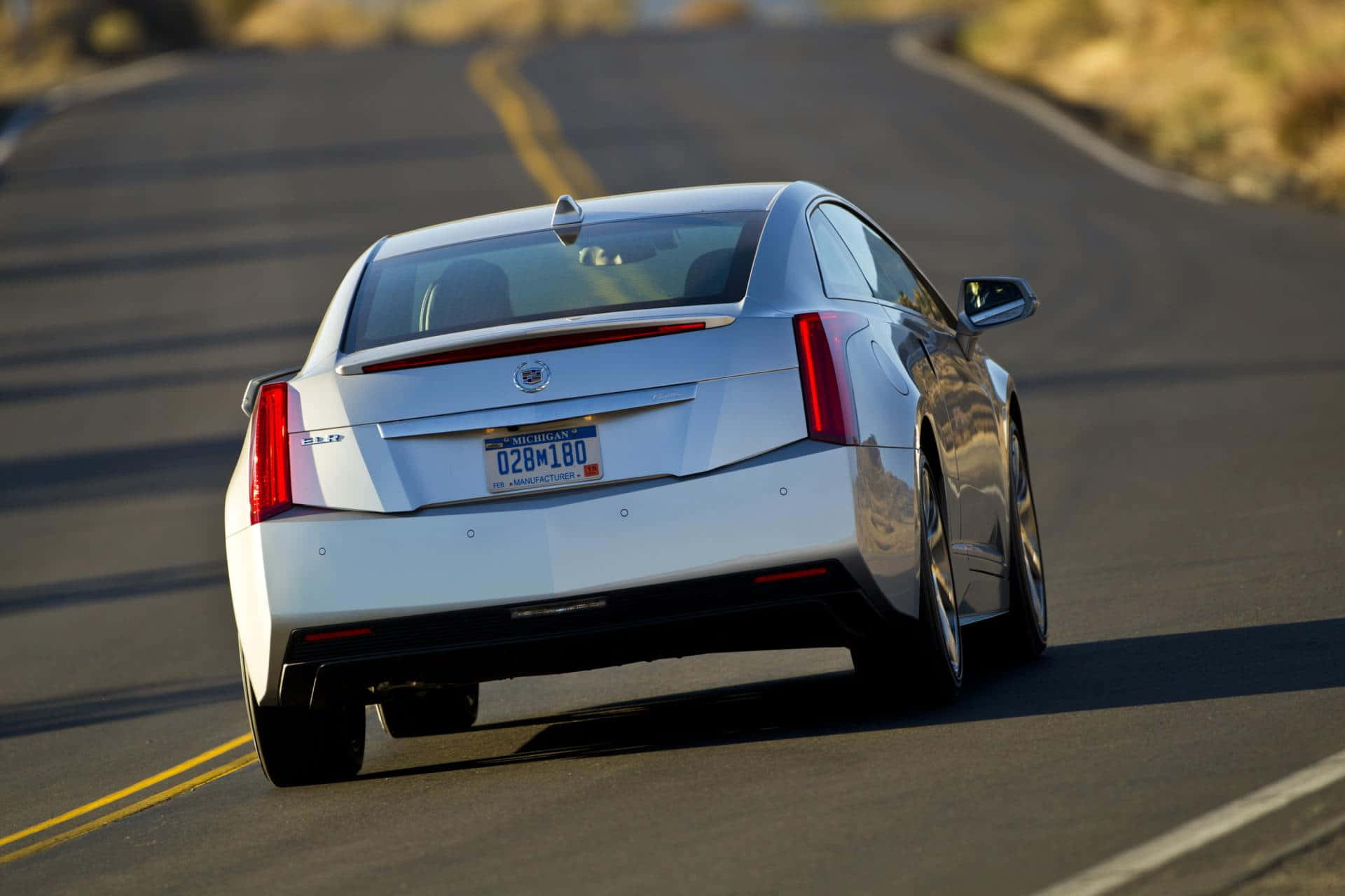 Cadillac Elr 桌布 壁紙 — 一輛銀色 Cadillac ELR 在陽光明媚的蜿蜒道路上巡航，背景是金色的山丘。
