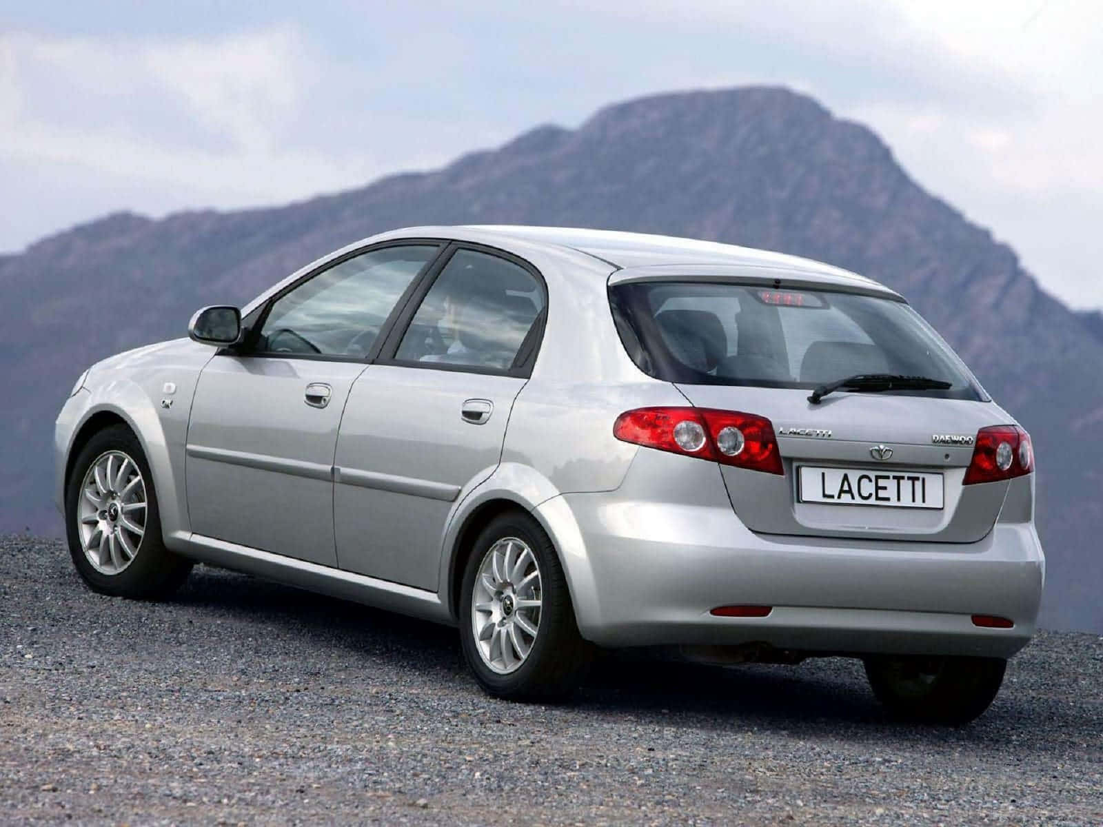 Daewoo 桌布 壁紙 — 一輛銀色 Vauxhall Lacetti 掀背車停在碎石上，背景是陰天下的崎嶇山脈。