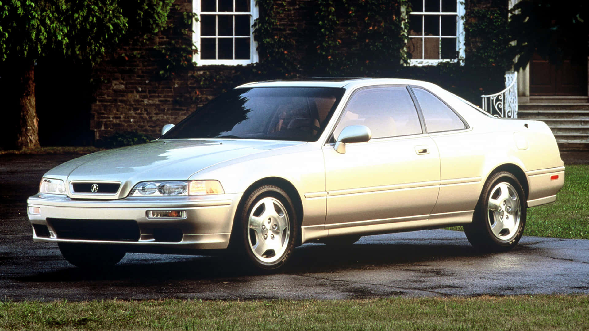 Acura Legend 桌布 壁紙 — 一輛銀色Acura NSX雙門跑車在柔和日光下閃閃發光，停泊在濕漉漉的車道上，旁邊是一間磚牆上爬滿常春藤的房子。