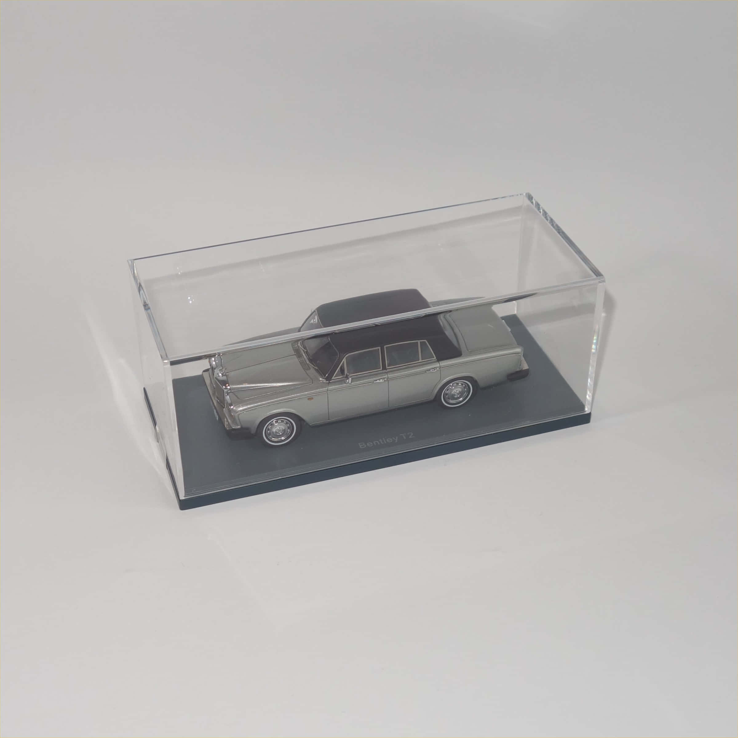 Bentley T2 桌布 壁紙 — 一輛銀色Bentley T2模型車，黑色車頂，展示在灰色底座上的透明亞加力盒中。