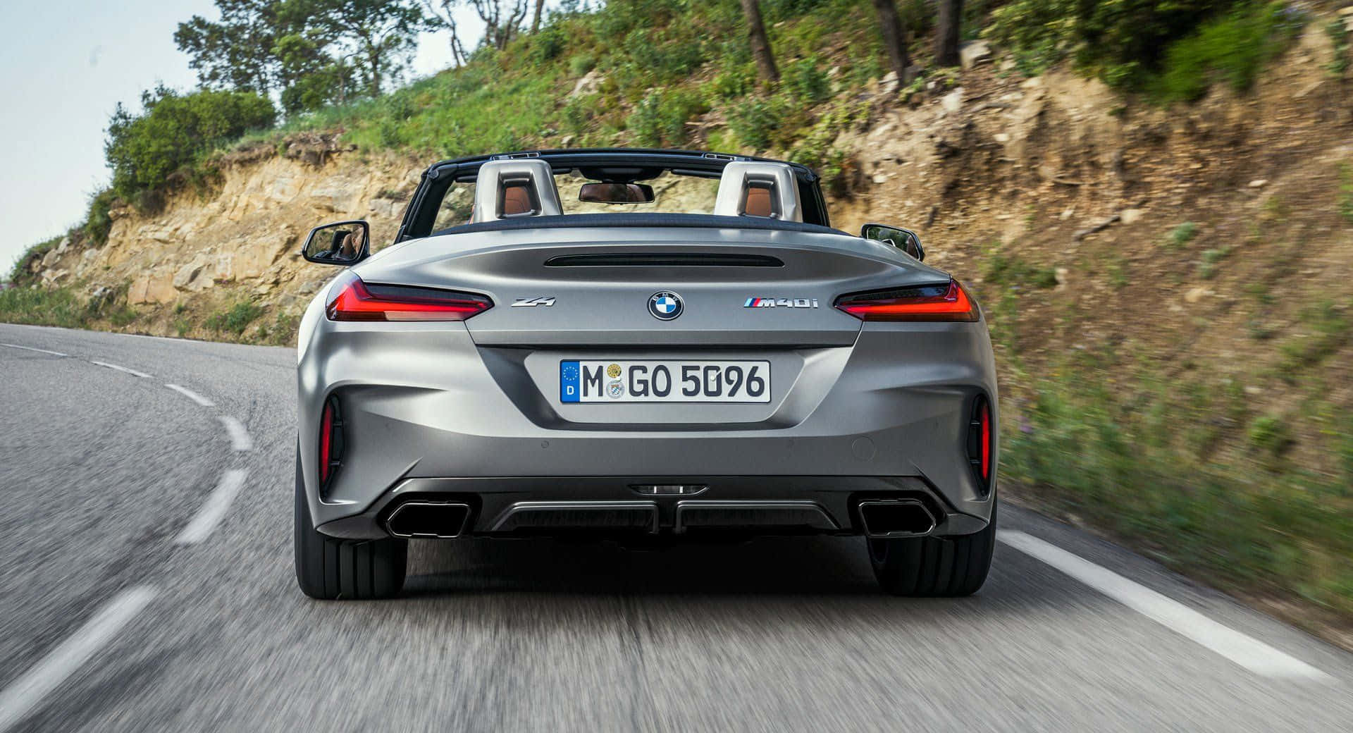 Bmw Z4 桌布 壁紙 — 一輛銀色BMW M4 Convertible在蜿蜒的山路上疾馳，兩旁是茂密的綠植和岩石峭壁。