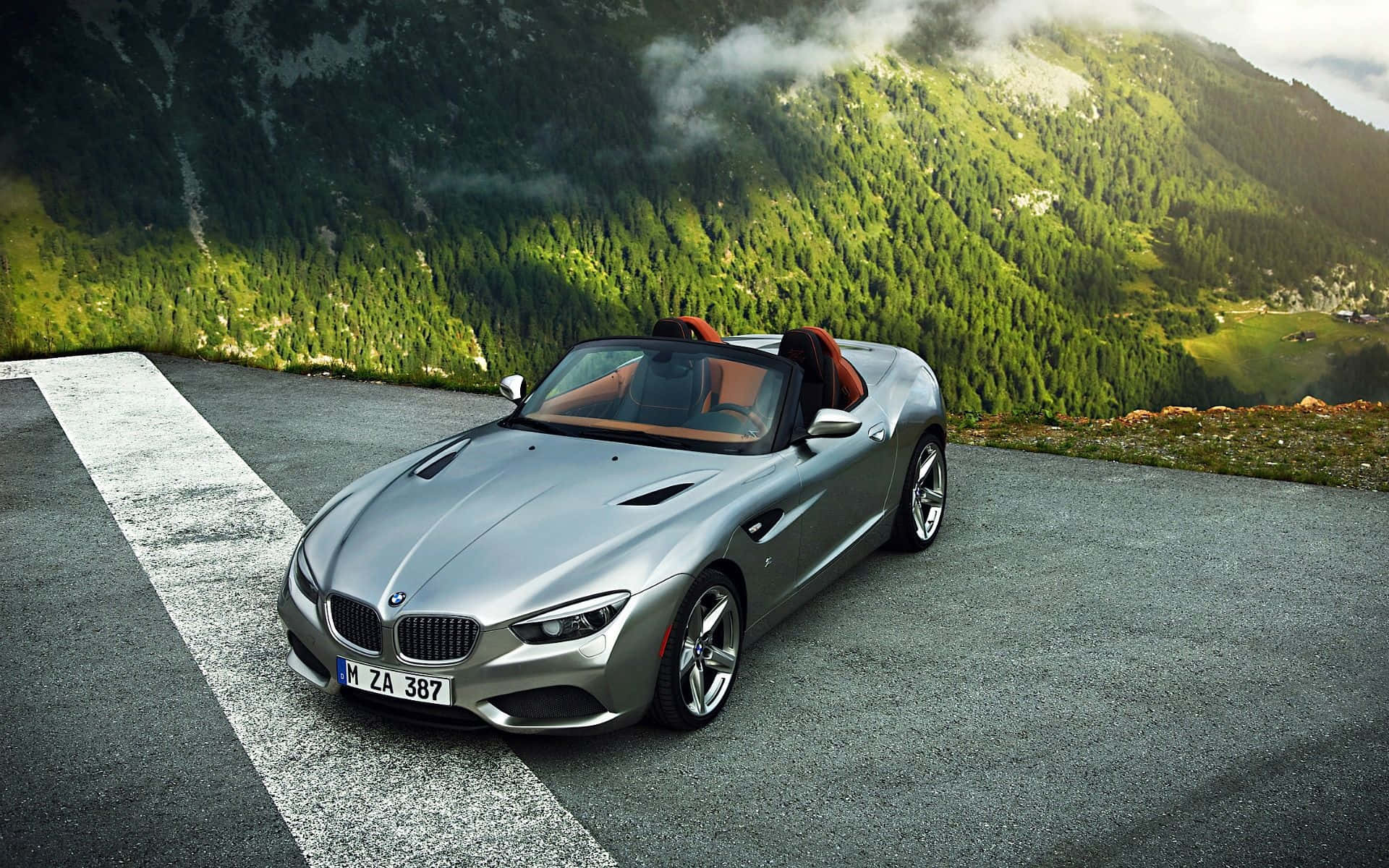 Bmw Z4 桌布 壁紙 — 一輛銀色BMW Z8開篷車停泊在山路上，背景是茂密的綠色森林和霧氣籠罩的山峰。