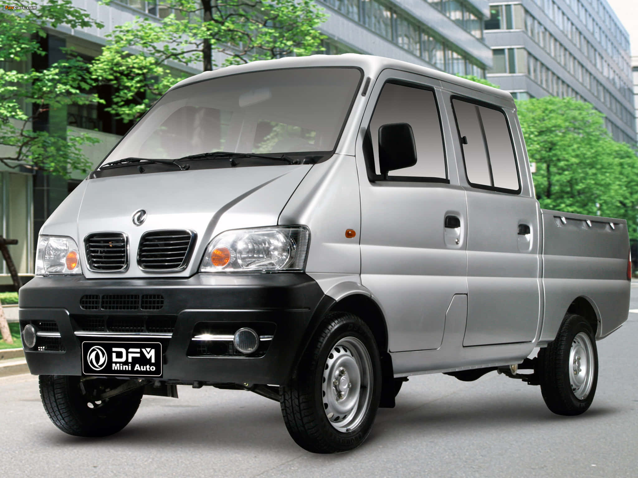 Dongfeng 桌布 壁紙 — 一輛銀色DFY Mini Auto小型貨車停泊在城市的街道上，背景有綠樹和現代建築。