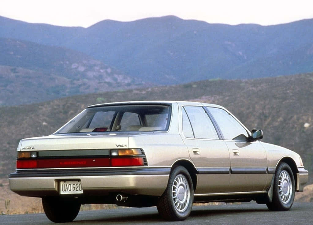 Acura Legend 桌布 壁紙 — 一輛銀色Lexus LS400房車停泊在道路上，背景是連綿起伏的山丘和山脈，天空朦朧。