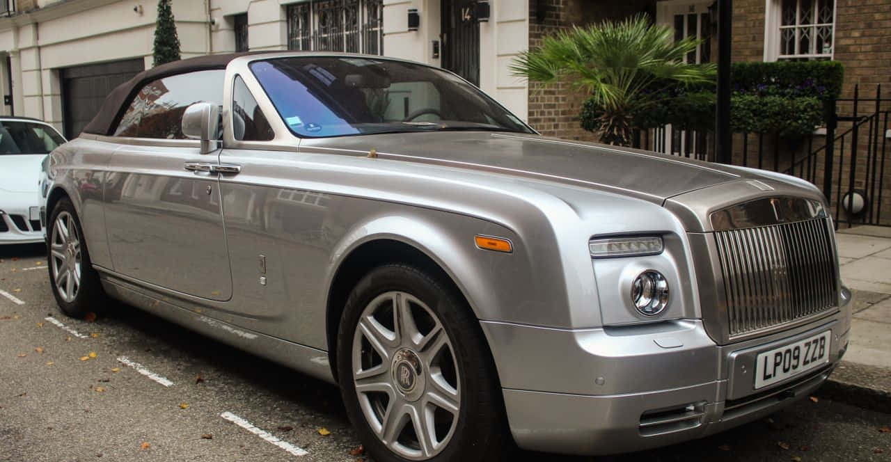 Rolls Royce Phantom Drophead Coupe 桌布 壁紙 — 一輛銀色勞斯萊斯 Phantom Drophead Coupe 停泊在住宅街道上，行人路上散落著秋天的落葉。
