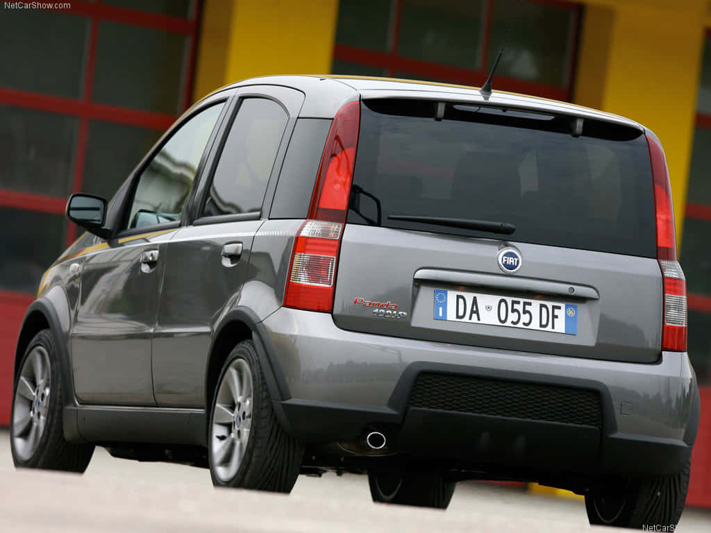 Fiat Panda 桌布 壁紙 — 一輛銀色嘅Fiat Panda 4x4停泊喺度，背景係一棟充滿活力嘅紅黃色建築物。
