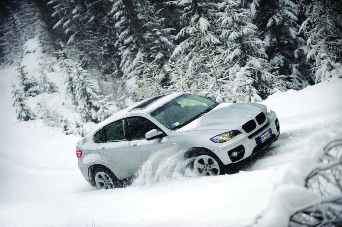 Winter Driving 桌布 壁紙 — 一輛銀色寶馬X6在白雪覆蓋的松樹林中穿越深雪行駛。