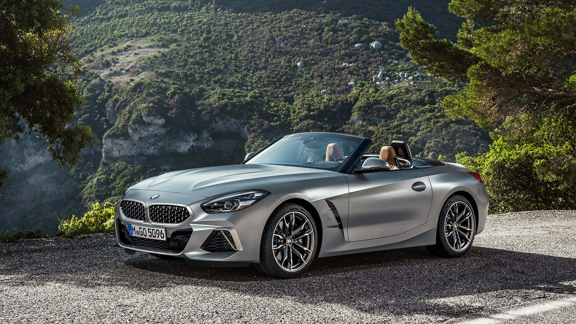 Bmw Z4 桌布 壁紙 — 一輛銀色寶馬Z4開篷車停在碎石路上，兩個人正在欣賞風景如畫的山景。