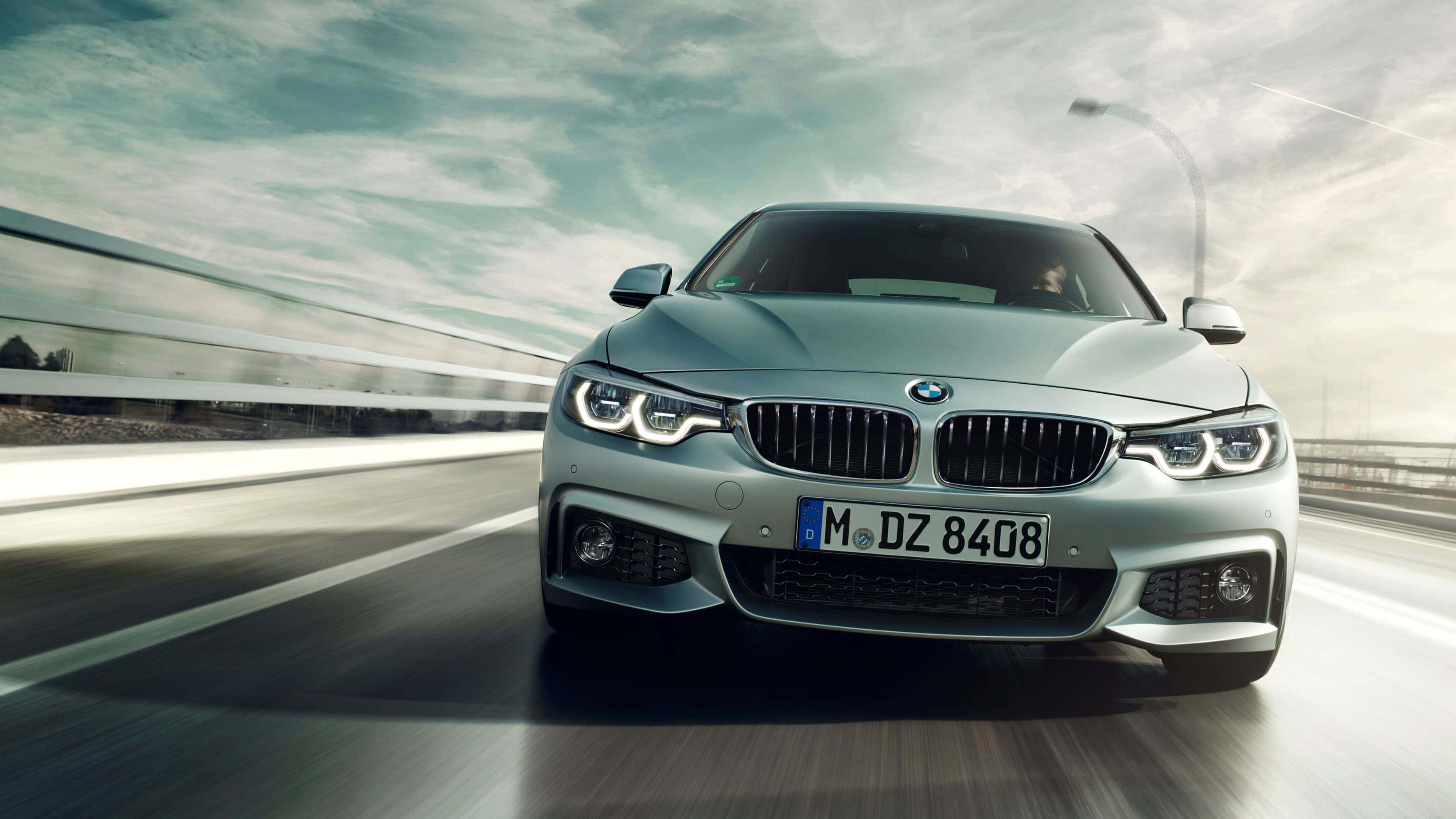 Bmw 4 Series 桌布 壁紙 — 一輛銀色寶馬房車在高速公路上疾馳，在陰天天空下帶有動態模糊效果。