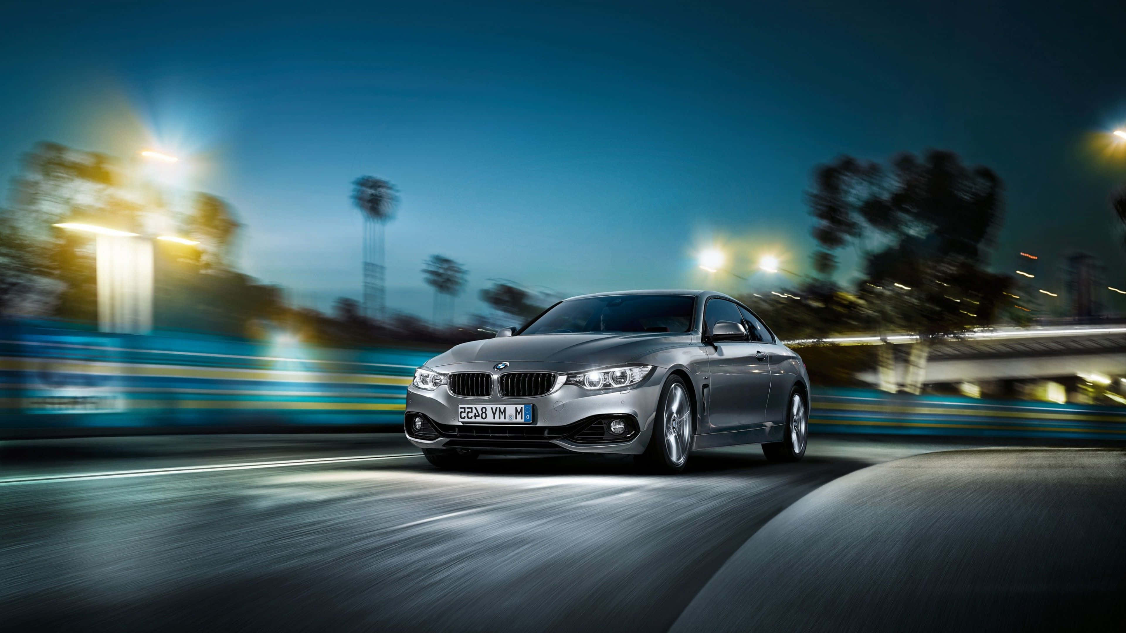 Bmw 4 Series 桌布 壁紙 — 一輛銀色寶馬轎跑車在夜間的城市道路上高速行駛，模糊的光線掠過。