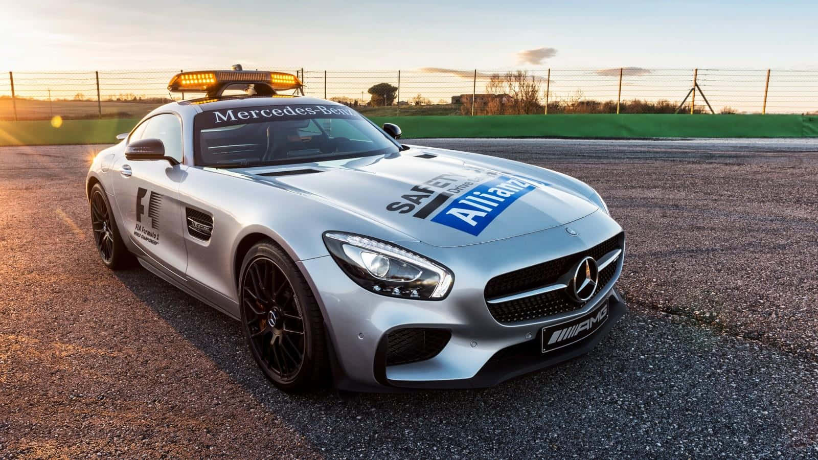 Safety Car 桌布 壁紙 — 一輛銀色平治AMG GT安全車，閃爍著警示燈，在黃金時段停泊在賽車場上。