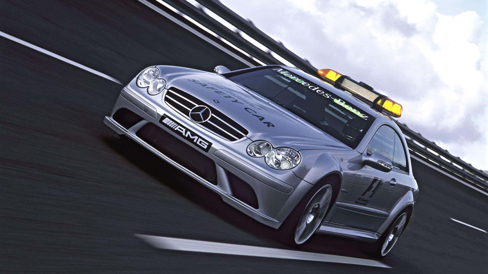 Safety Car 桌布 壁紙 — 一輛銀色平治AMG安全車在陰天下的賽道上疾馳，動態模糊效果突顯其速度。
