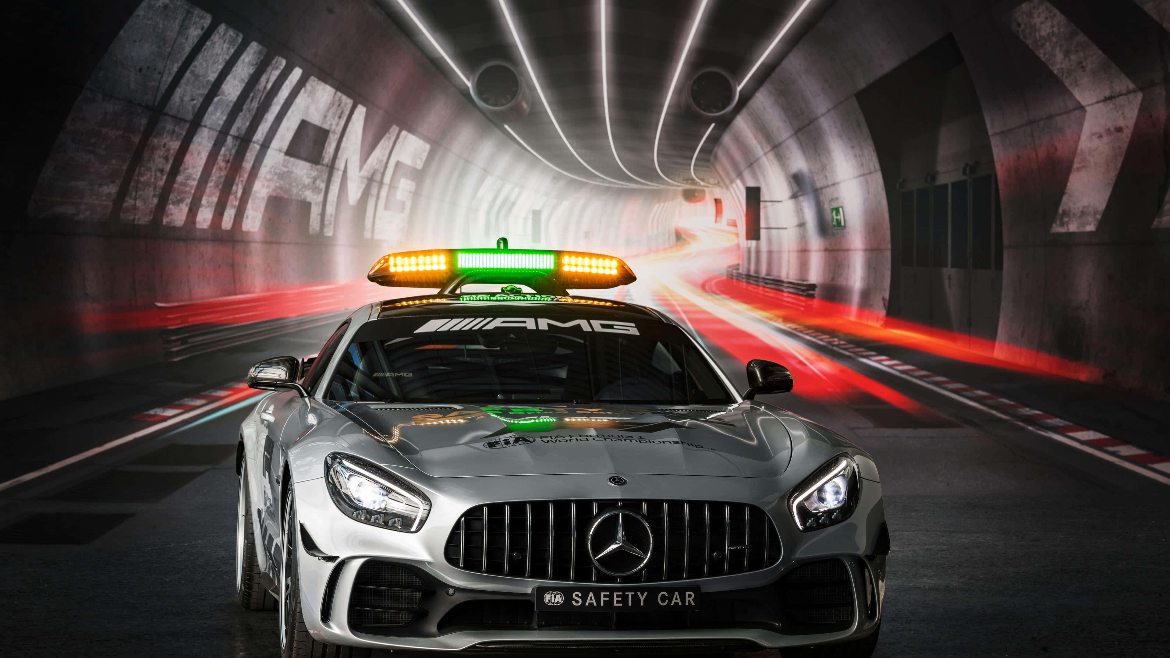 Safety Car 桌布 壁紙 — 一輛銀色平治AMG安全車閃著燈，穿過隧道，留下發光的紅色動態軌跡。