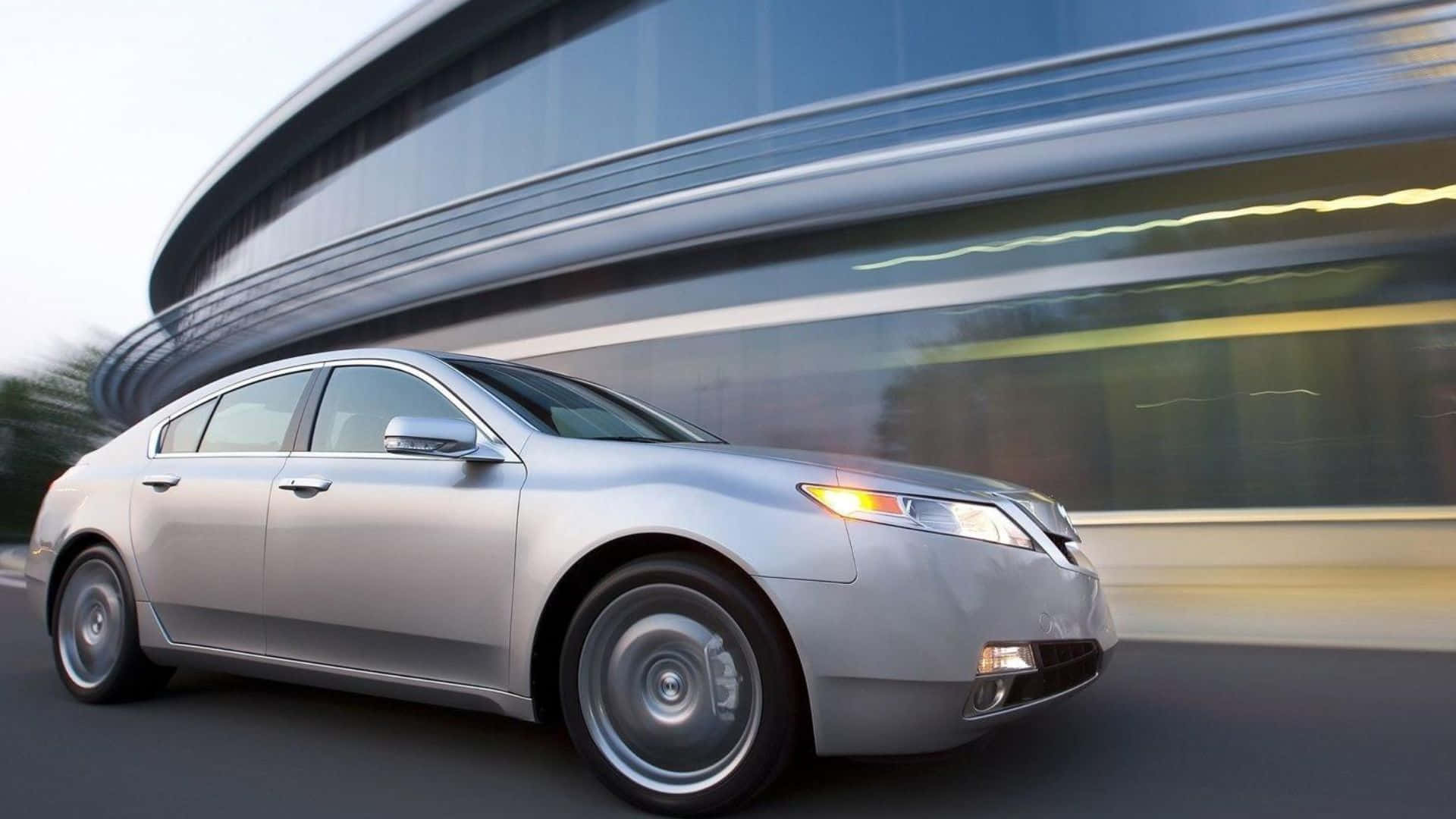 Acura Tl 桌布 壁紙 — 一輛銀色房車高速駛過現代玻璃建築，動態模糊強調了速度。