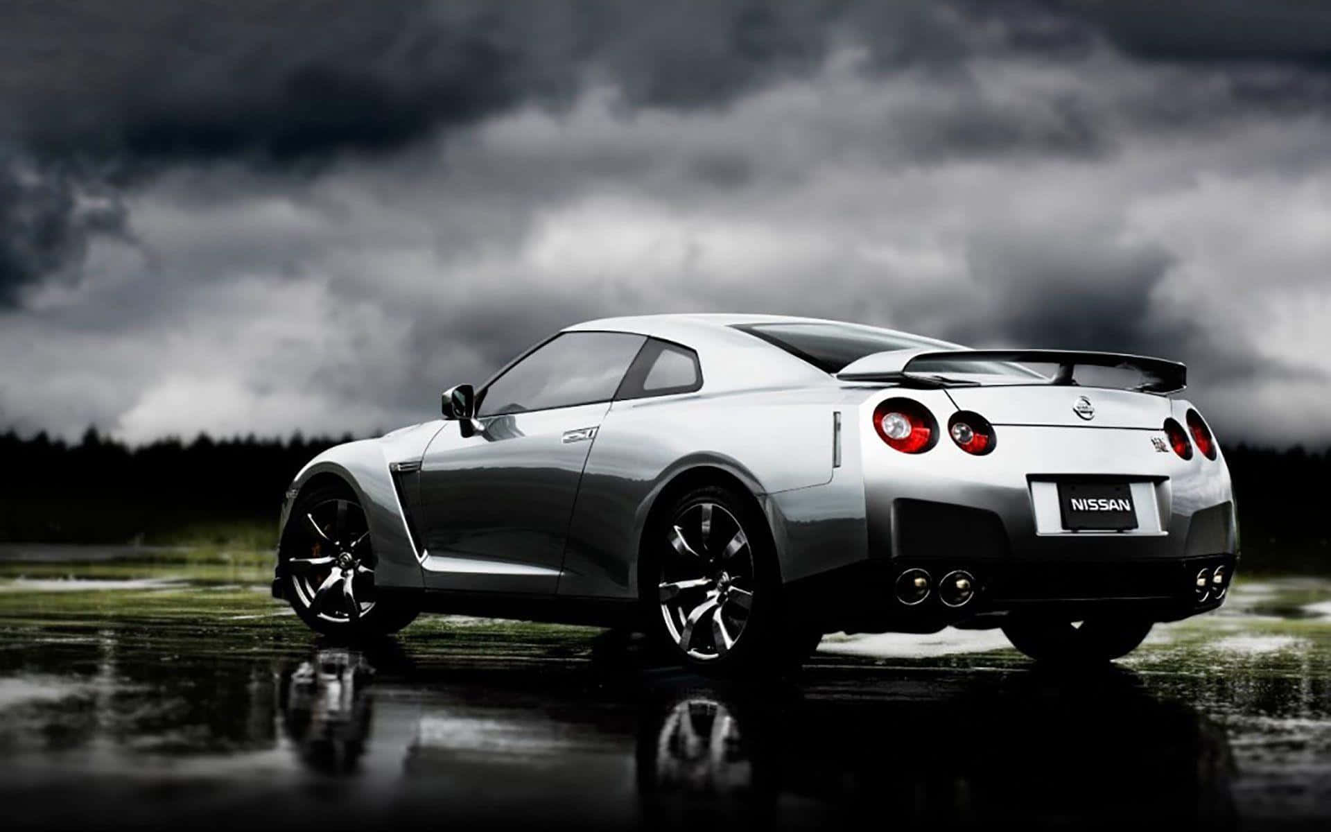 Best Car 桌布 壁紙 — 一輛銀色日產GT-R跑車在濕滑路面上閃閃發光，背景是烏雲密佈的暴風雨天空。