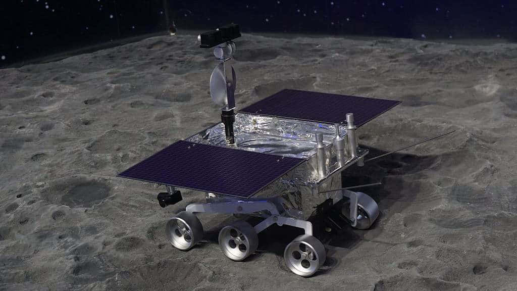 Lunar Rover 桌布 壁紙 — 一輛銀色月球車配備太陽能板，在星空下探索佈滿隕石坑的月球表面。