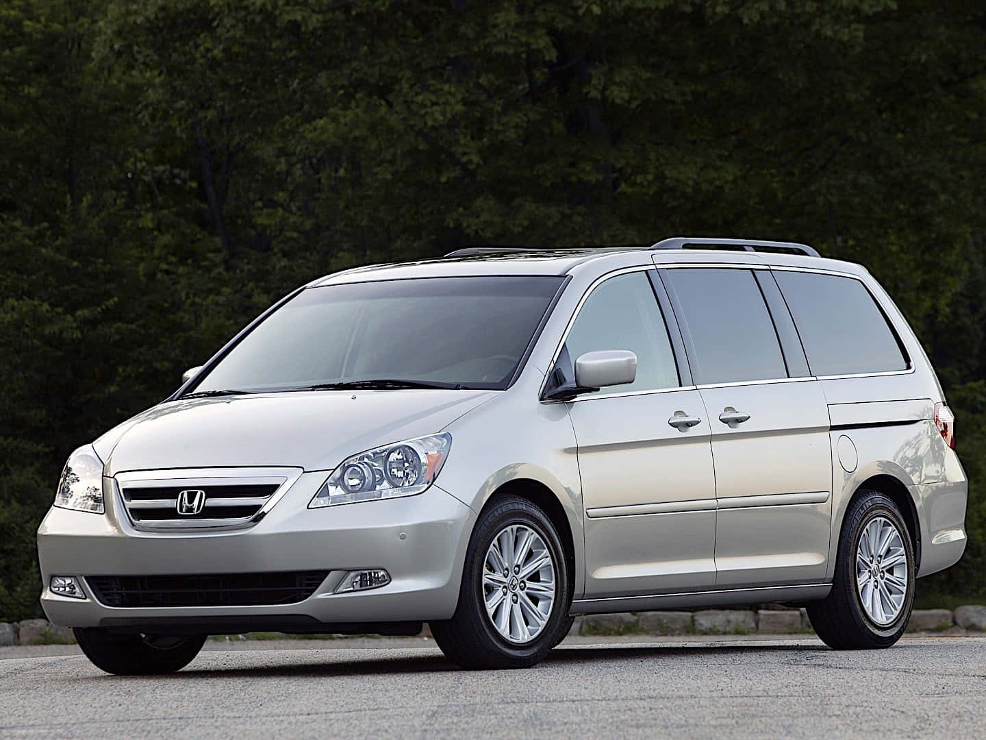 Honda Odyssey 桌布 壁紙 — 一輛銀色本田Odyssey小型貨車停在路面上，背景是茂密的綠樹。