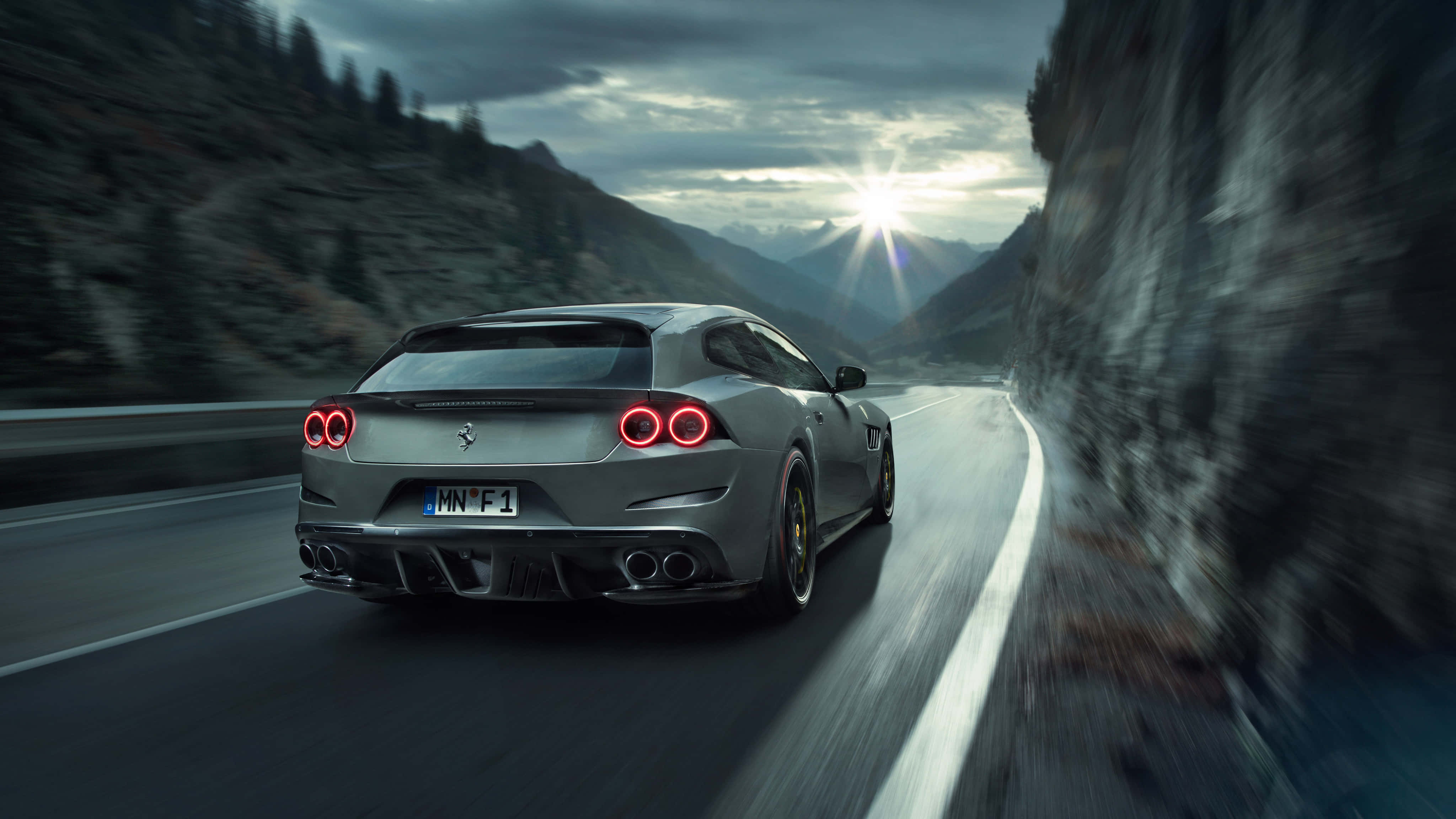 Ferrari Gtc4lusso 桌布 壁紙 — 一輛銀色法拉利跑車在日落時分沿著蜿蜒的山路疾馳，紅色尾燈閃爍發光。
