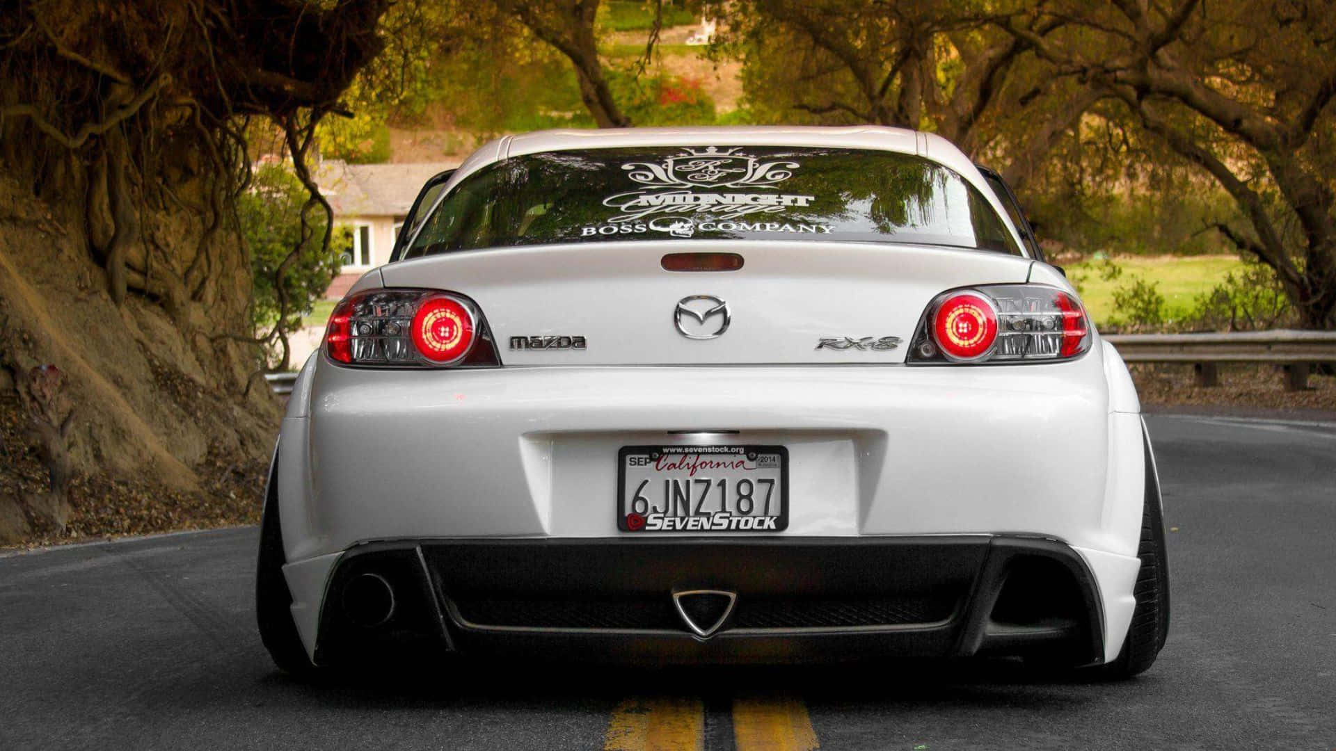 Mazda Rx-8 桌布 壁紙 — 一輛銀色萬事得RX-8跑車，紅色尾燈，在金色秋光照耀下行駛在樹木成行的道路上。
