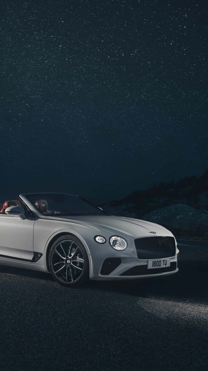 Bentley Continental Gt 桌布 壁紙 — 一輛銀色賓利開篷車停泊在星空下，車內有兩個人。