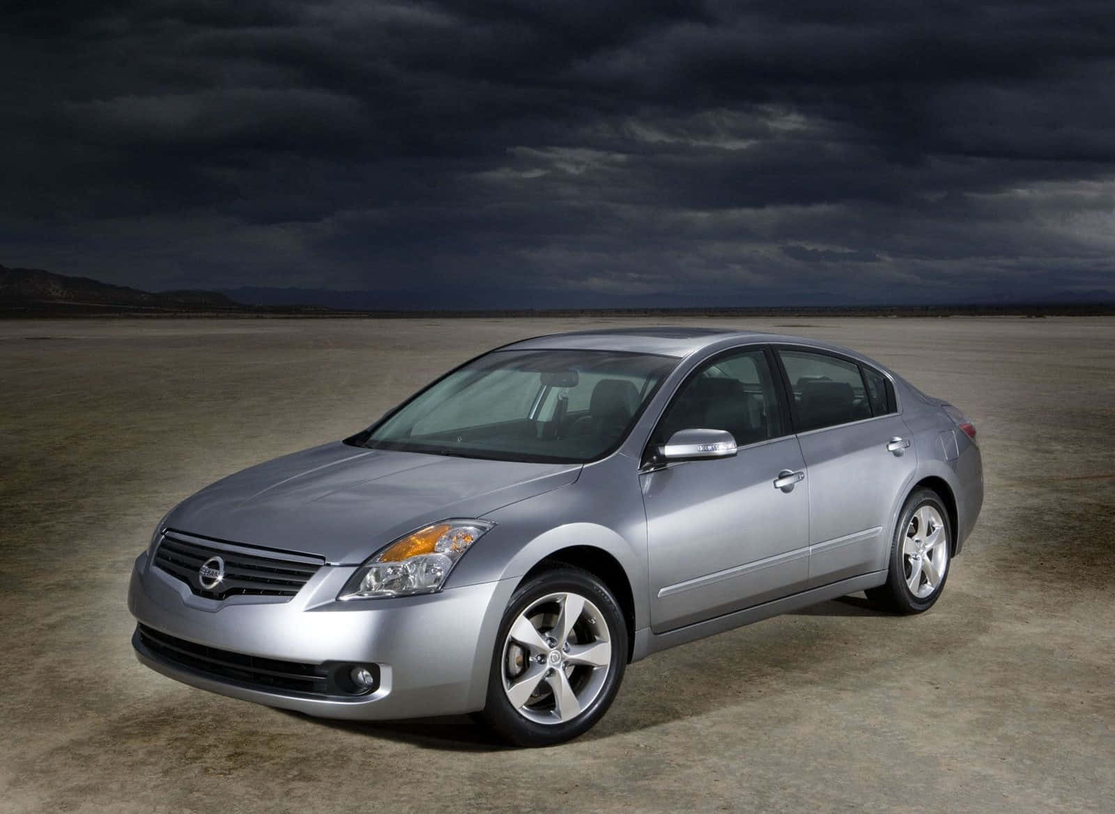Nissan Altima 桌布 壁紙 — 一輛銀色轎車孤獨地停在荒蕪的沙漠中，頭頂上是烏雲密佈、風暴來臨的戲劇性天空。
