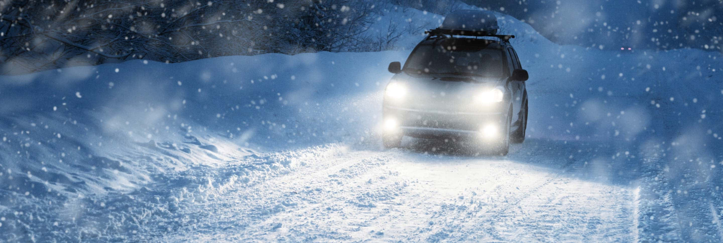 Winter Driving 桌布 壁紙 — 一輛雪地摩托車穿過暴風雪，明亮的車頭燈照亮白色的雪堆和黑暗的樹木。