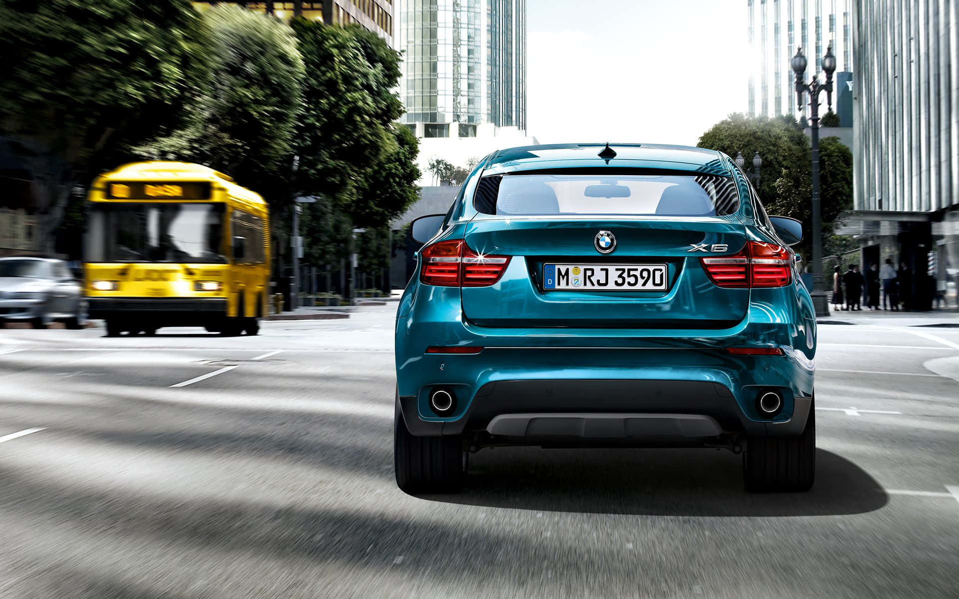 Bmw X6 桌布 壁紙 — 一輛青綠色的BMW X6 SUV在陽光明媚的城市街道上行駛，後面有一輛黃色巴士因移動而模糊。