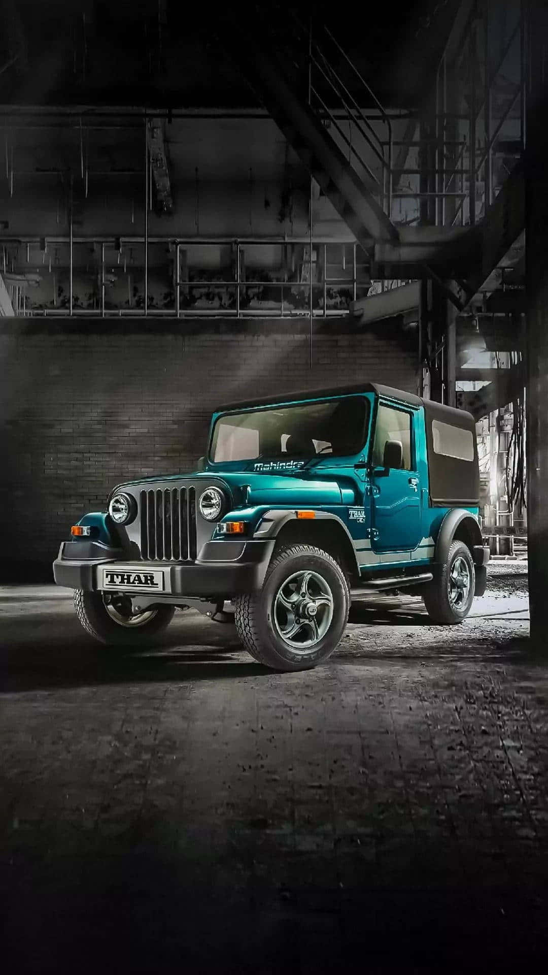 Jeep 動圖 桌布 壁紙 — 一輛青綠色的Mahindra Thar SUV在燈光昏暗的工業倉庫中，在戲劇性的聚光燈下傲然矗立。
