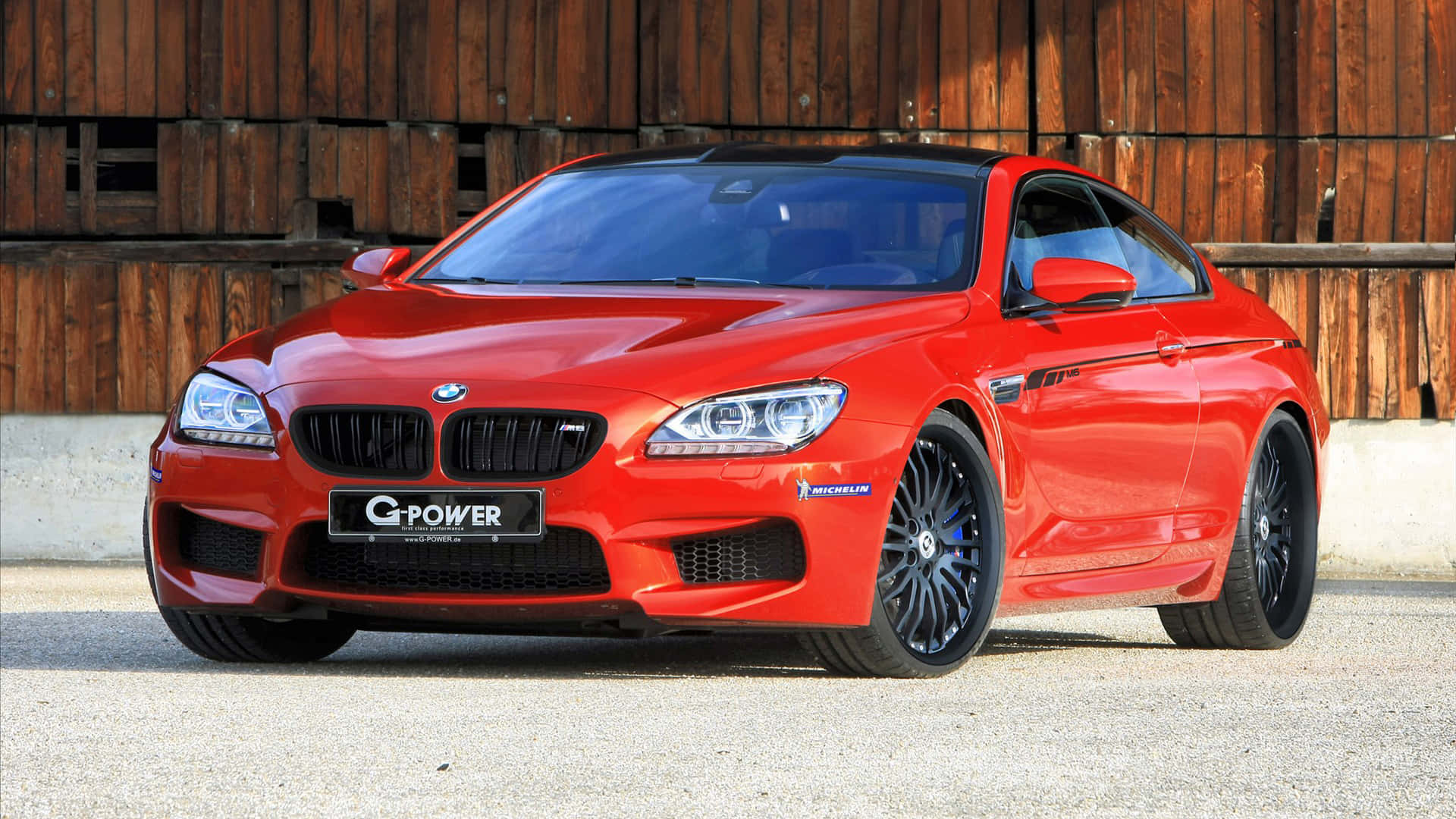Bmw M6 桌布 壁紙 — 一輛鮮紅色G-Power改裝BMW M6雙門跑車停泊在碎石上，前面是一道風化的木牆。
