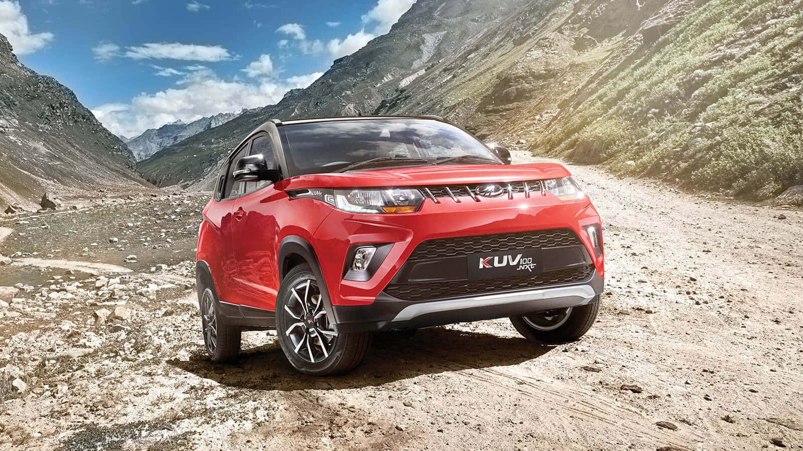 Mahindra 桌布 壁紙 — 一輛鮮紅色SUV停泊在岩石山徑上，天空湛藍，白雲點綴。