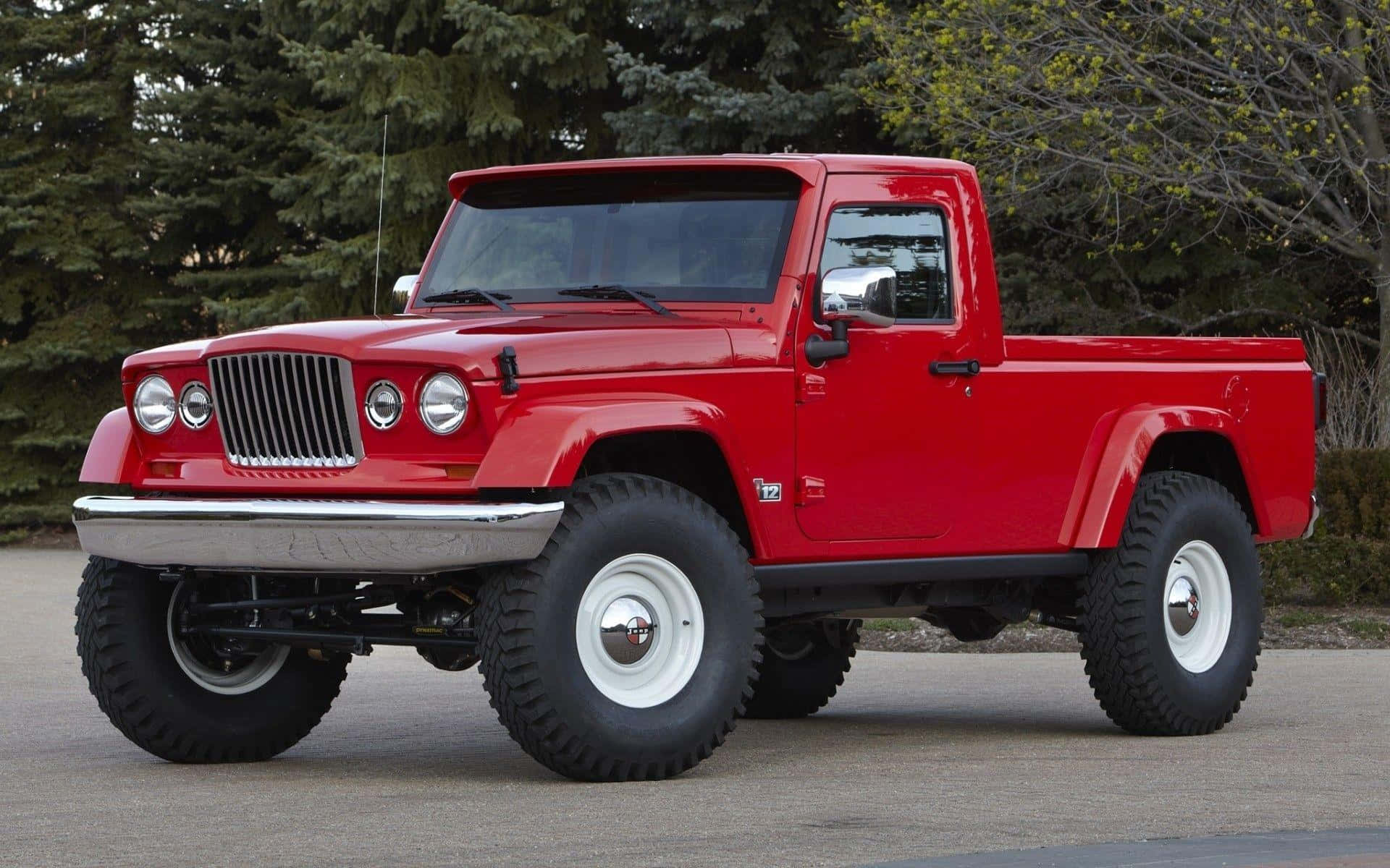 Jeep Gladiator 桌布 壁紙 — 一輛鮮紅色復古Jeep皮卡車，配備超大輪胎和鍍鉻裝飾，停在常綠樹旁的瀝青路面上。